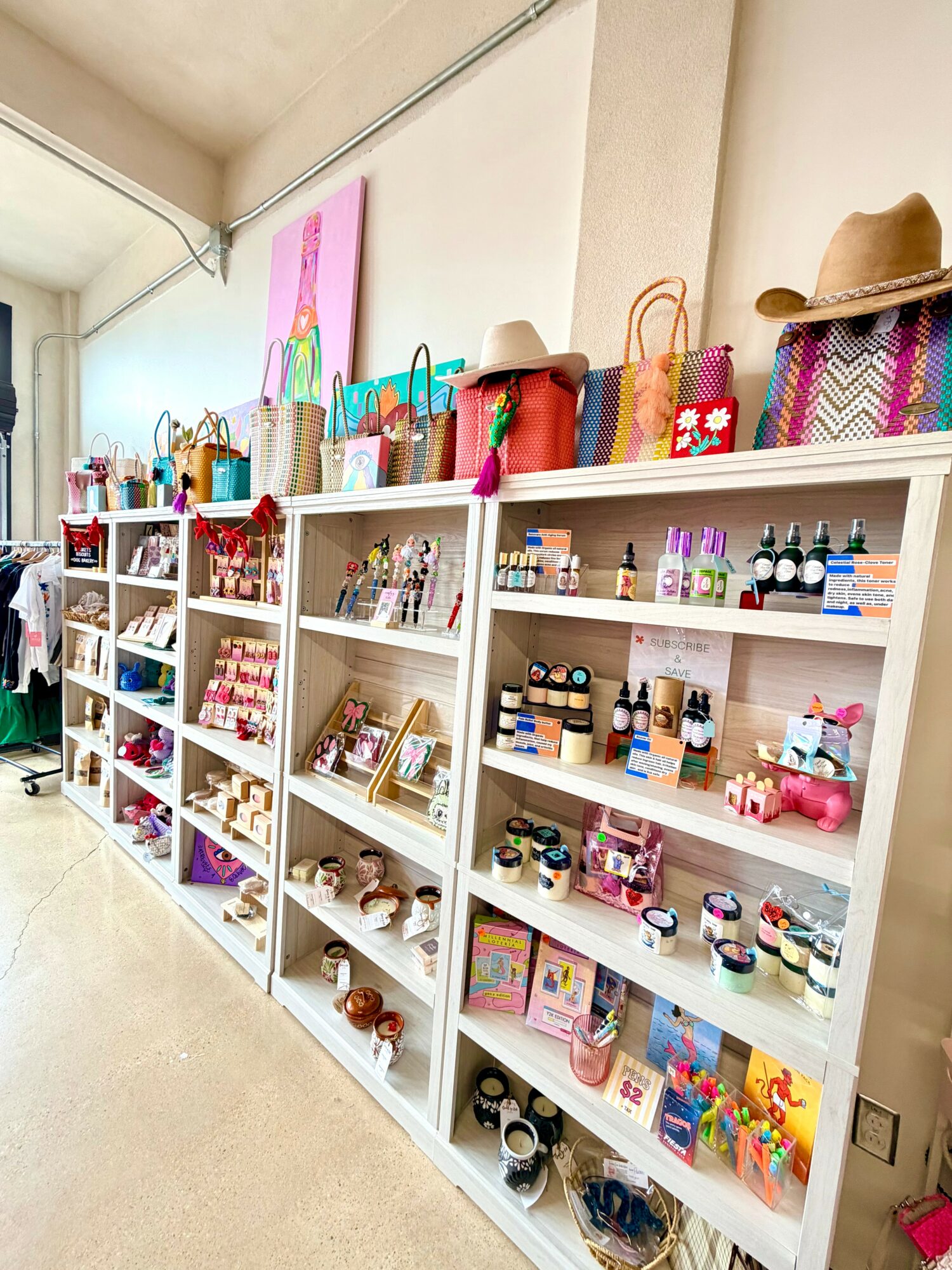 White shelves display colorful bags, hats, and small items in a store, with a beige wall and ceiling in the background.