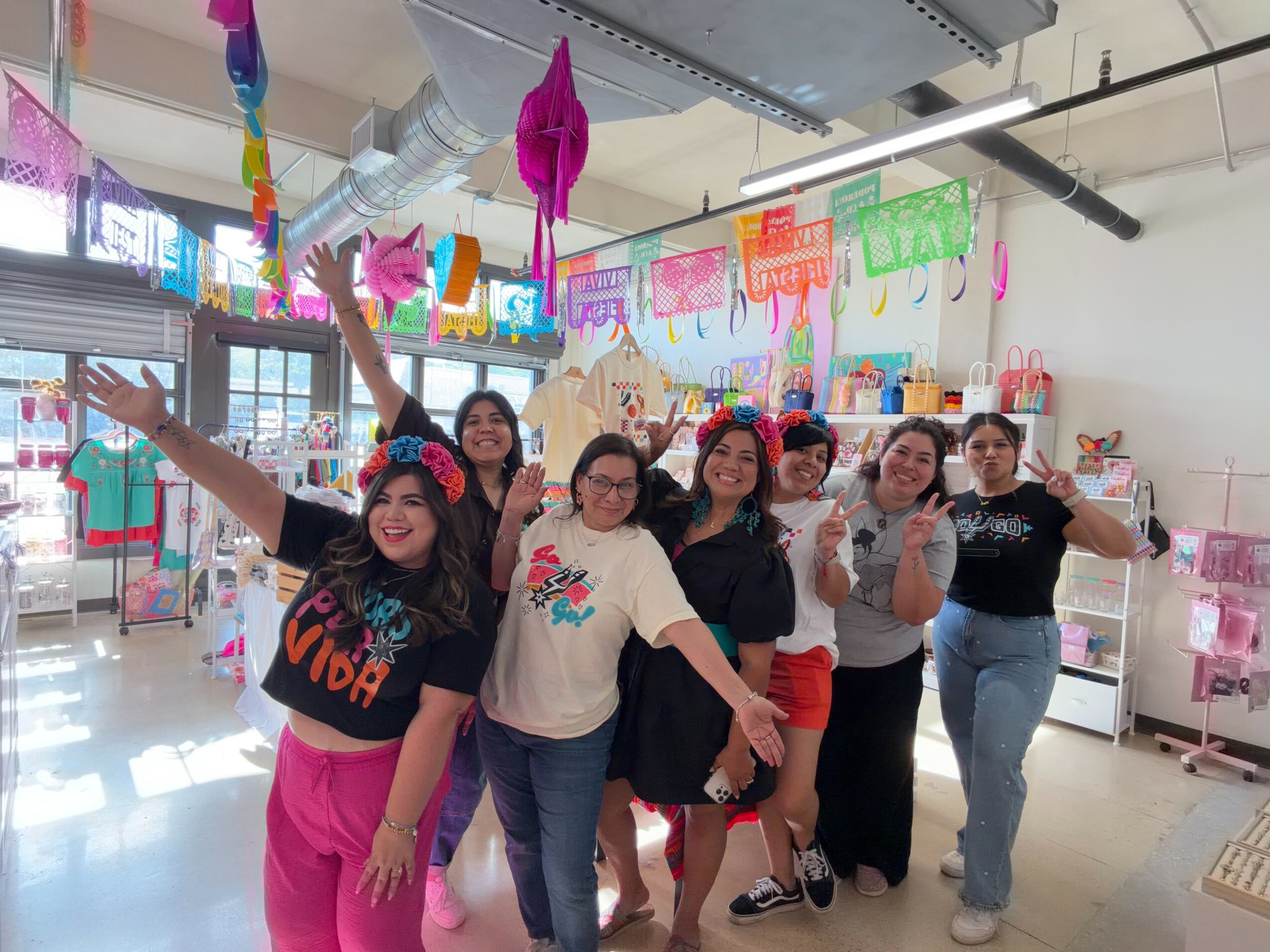 Group of women celebrating in a decorated room with colorful banners and crafts, smiling and posing for the photo.