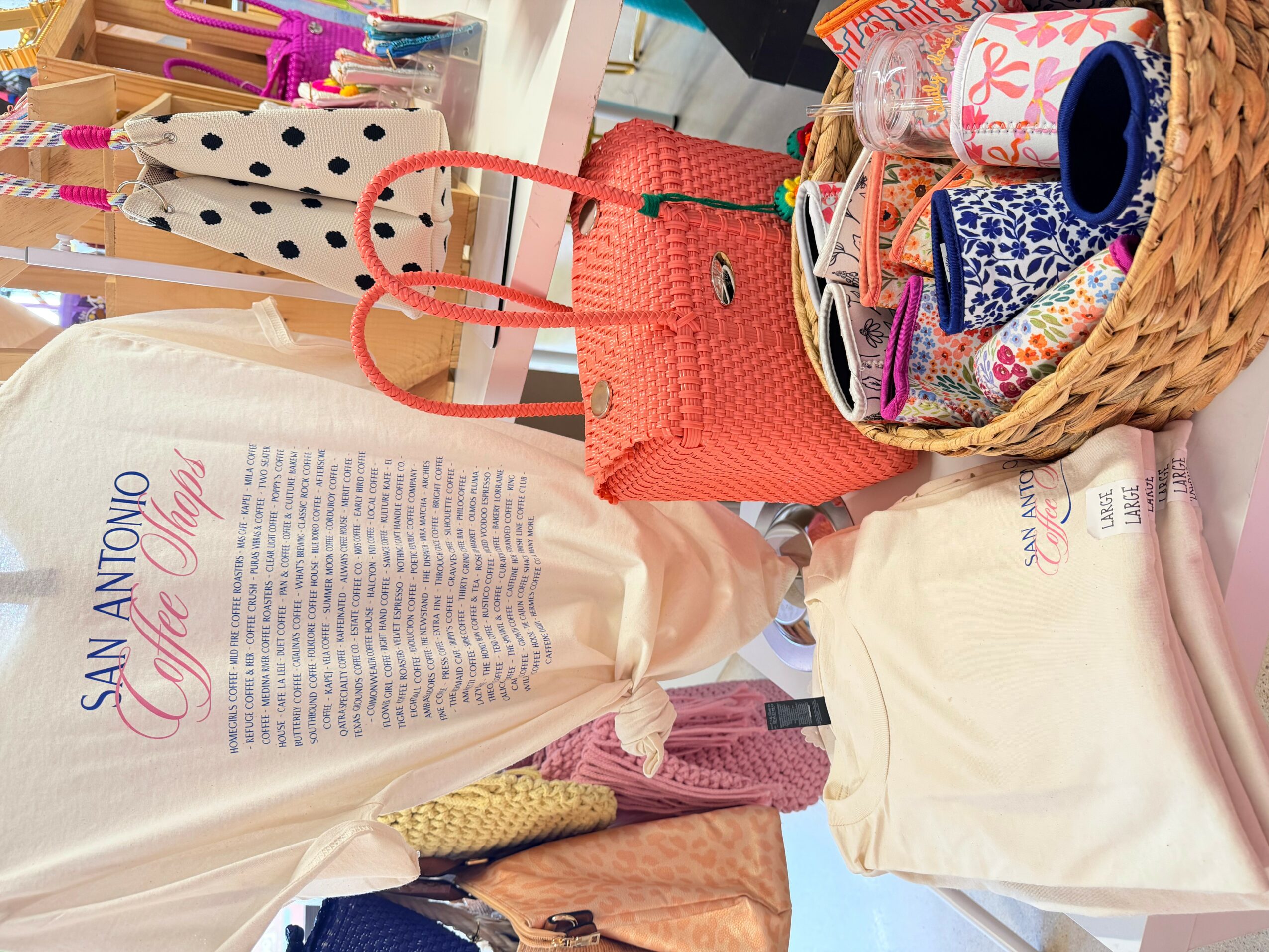 Display of colorful bags, fabric rolls, and accessories on a table at a market or store.