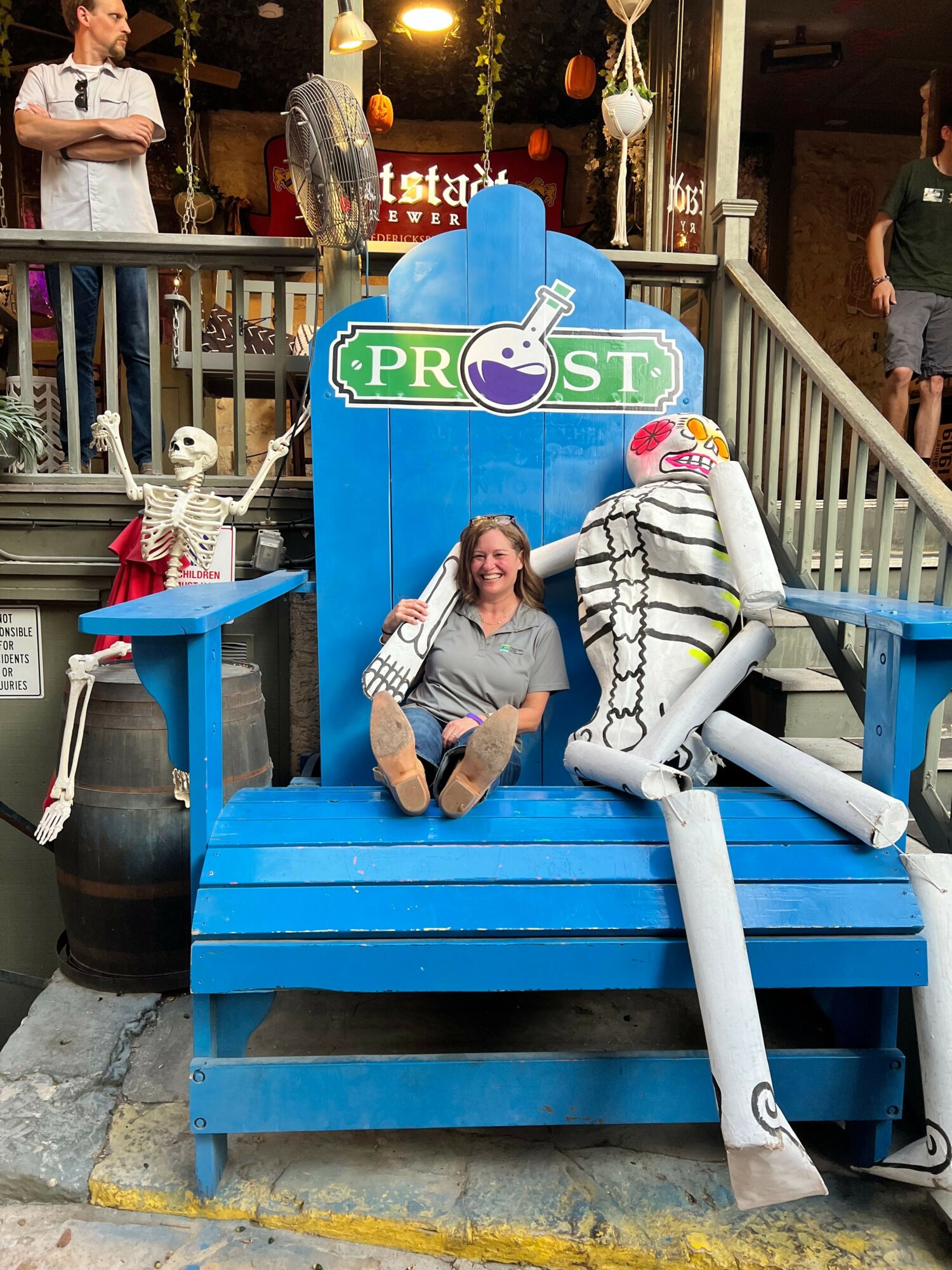 Person sitting on blue stairs with a backpack, holding a phone, near a PRIDE sign, in an outdoor setting.