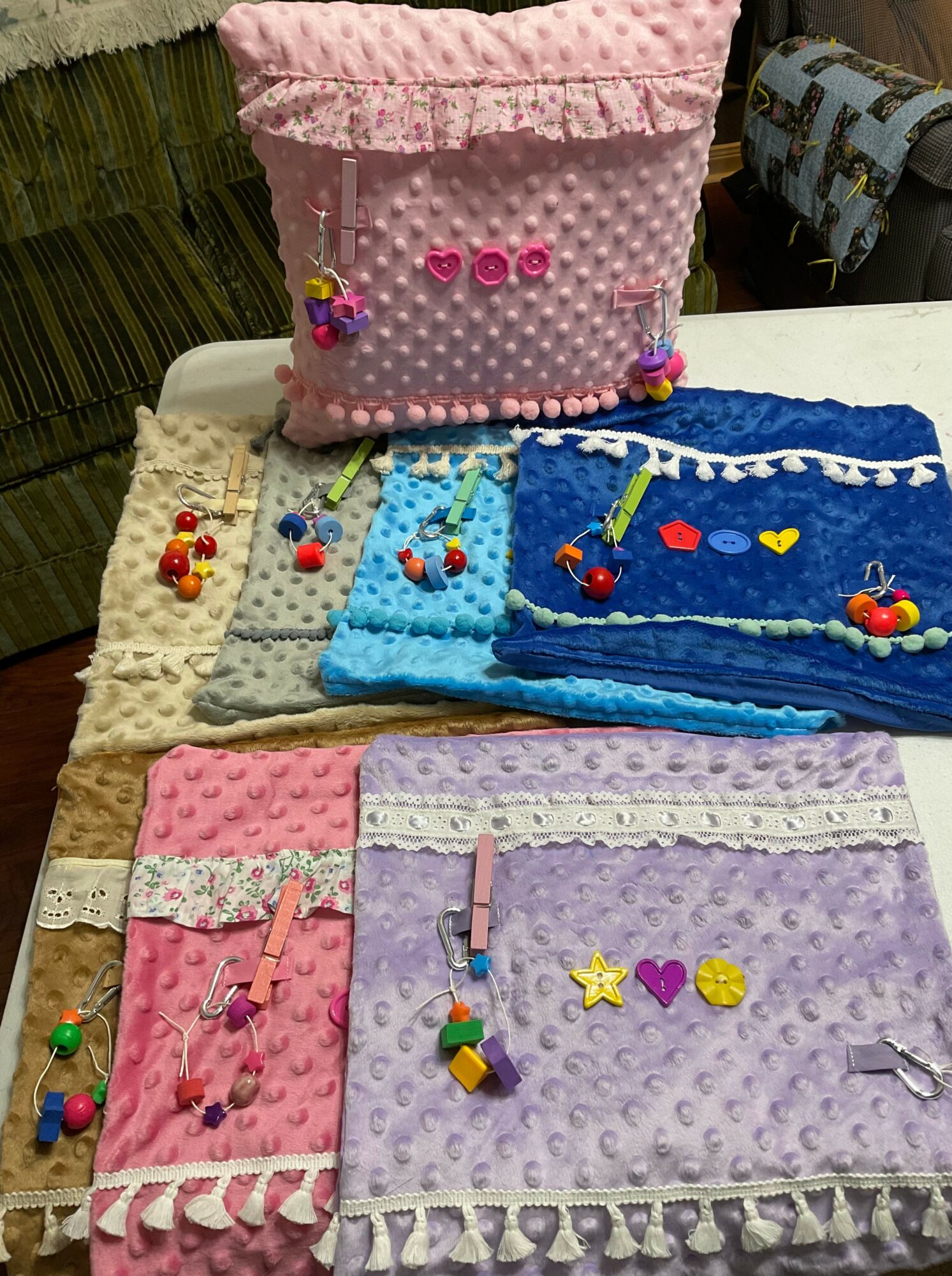 Six colorful handmade pouches with decorations, arranged on a table, in pink, white, blue, purple, and brown colors.