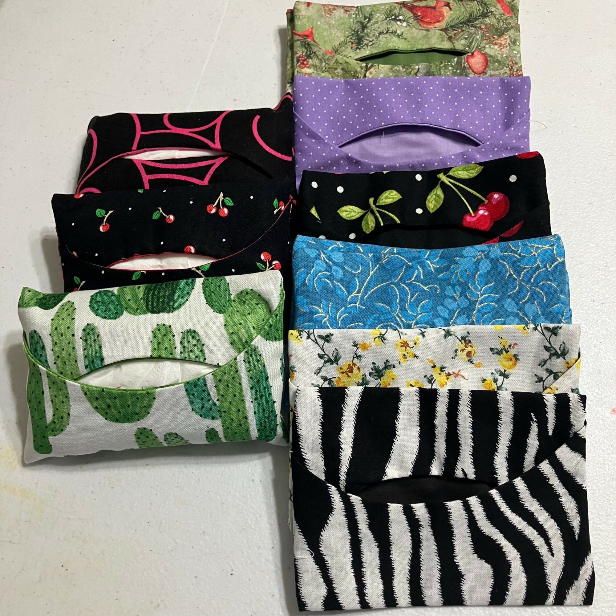 Eight fabric face masks with various patterns and colors, arranged in two columns on a white surface.