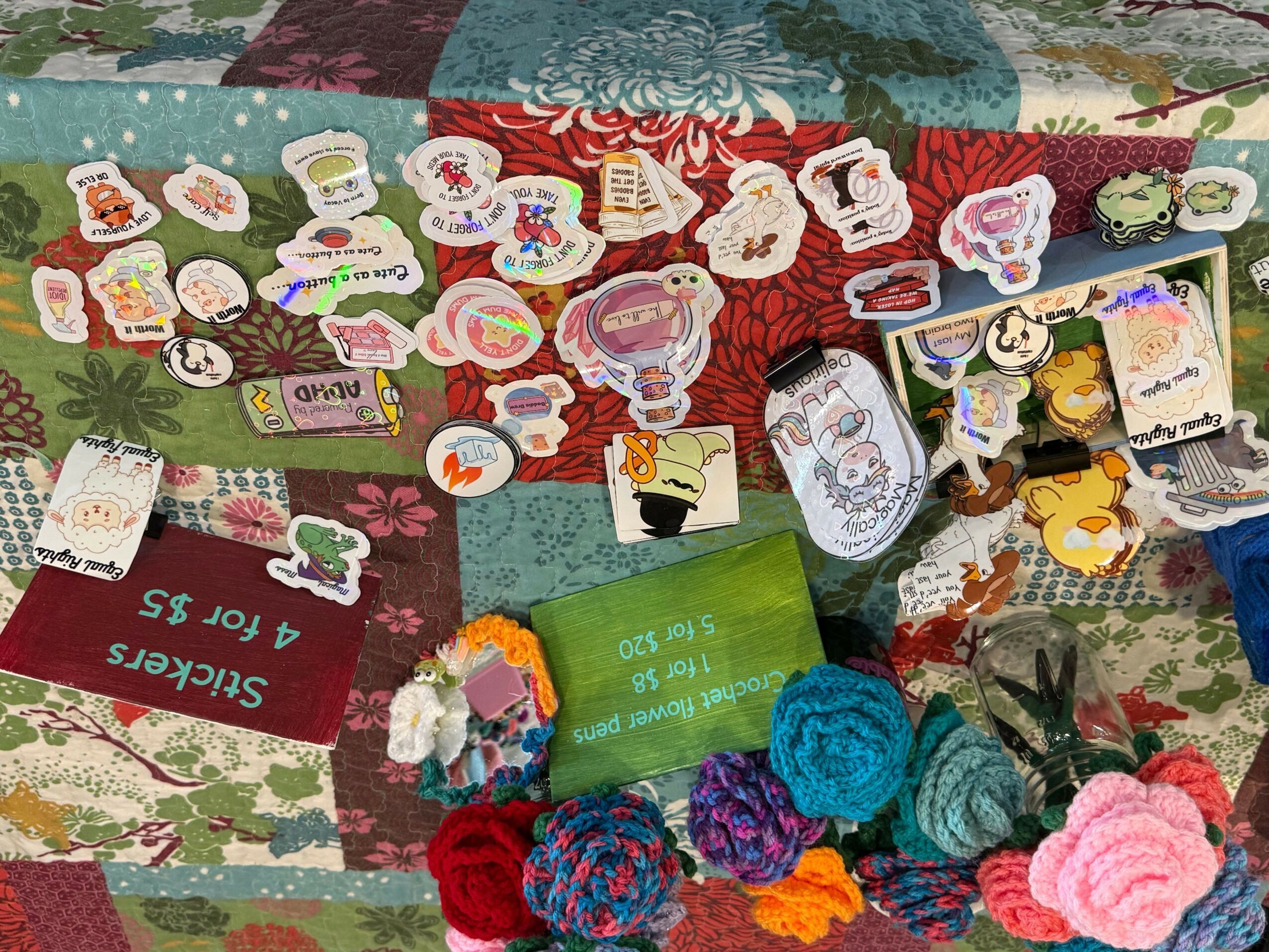 Display of colorful stickers, plush flowers, and small decorative items on a table with a red and green patterned cloth.