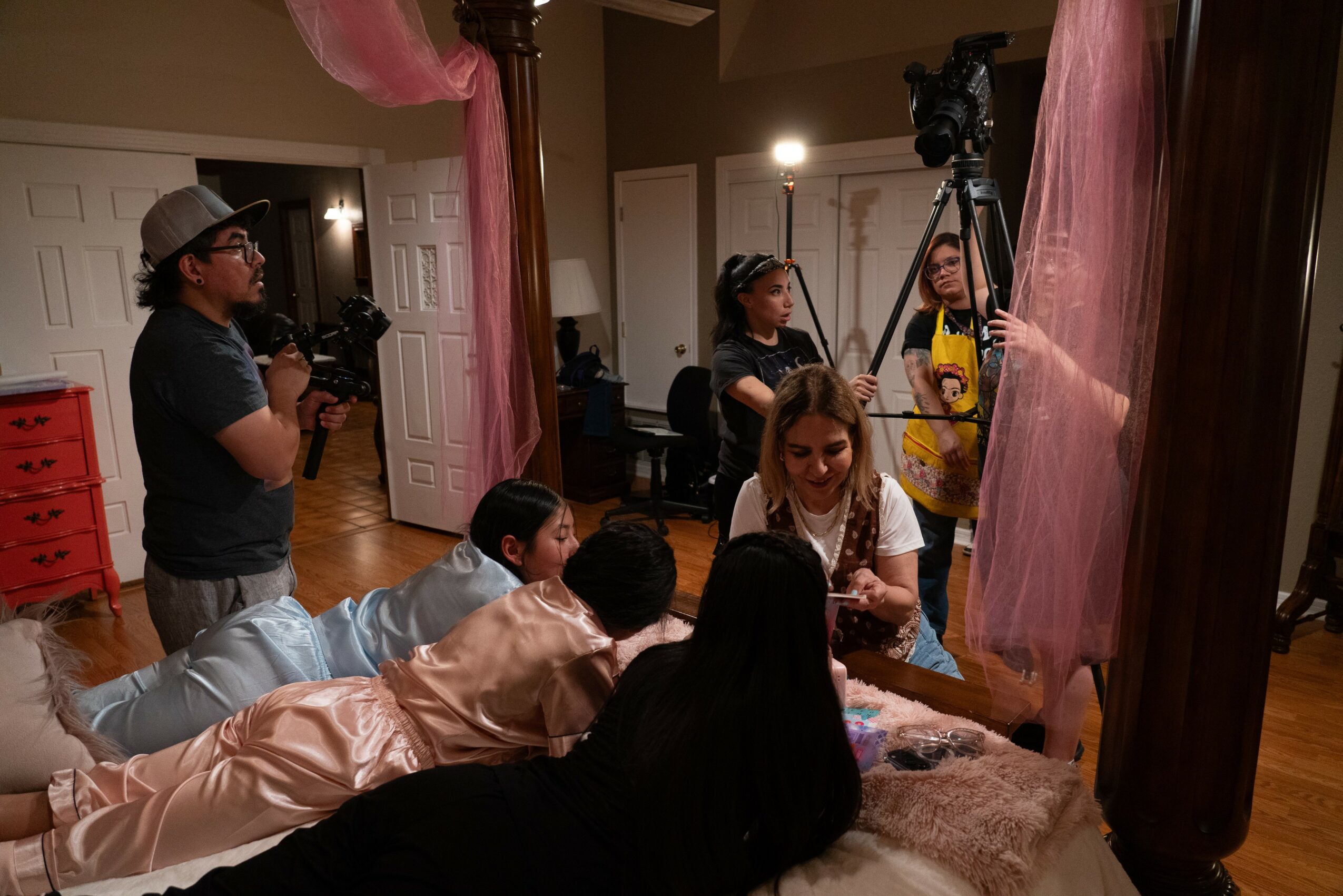 Group of people, including children and adults, in a room with cameras and lighting equipment, engaging in a photo shoot or filming.