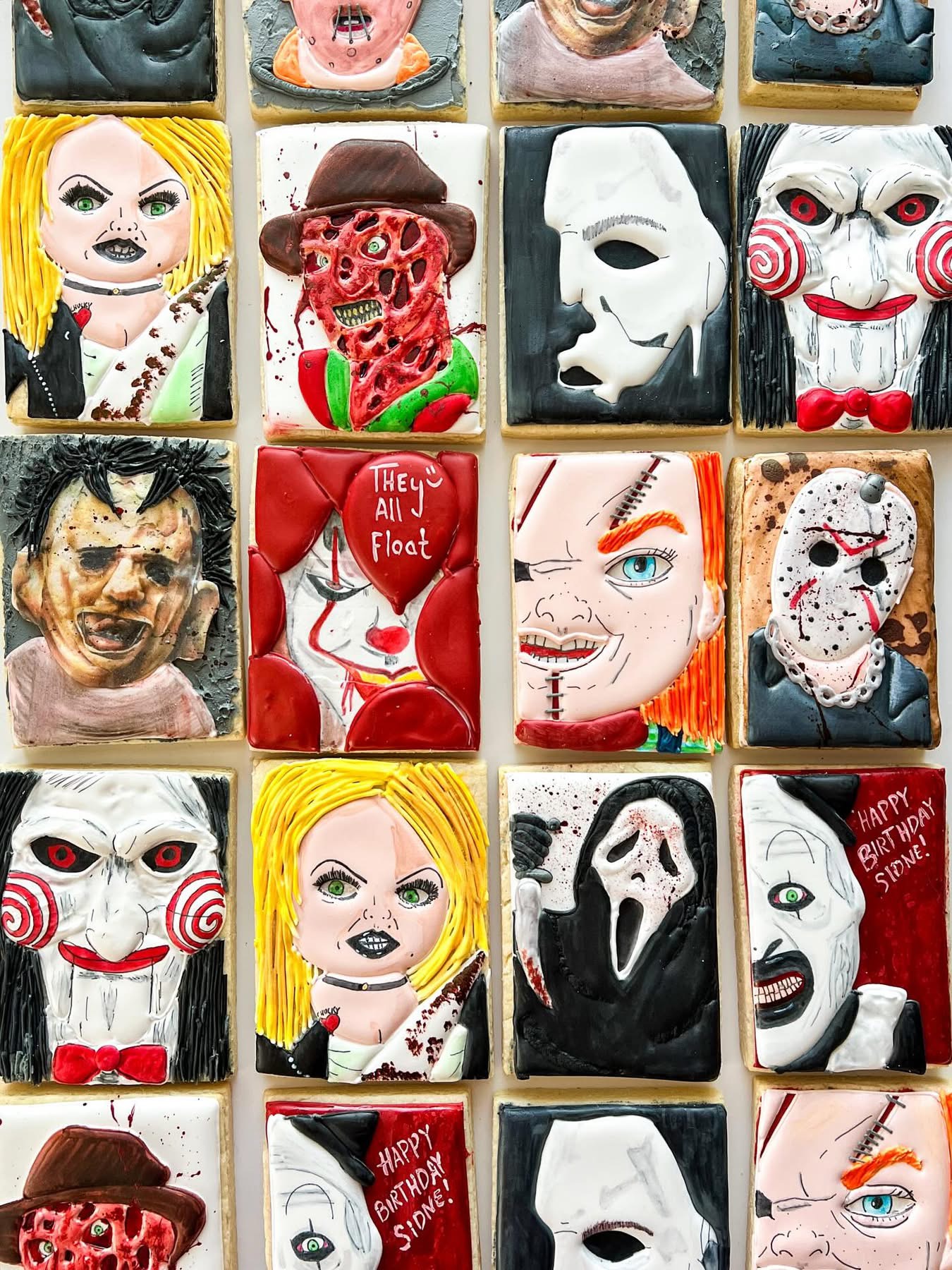 Collection of decorated cookies with horror and clown themes, featuring faces, masks, and characters, arranged in a grid.