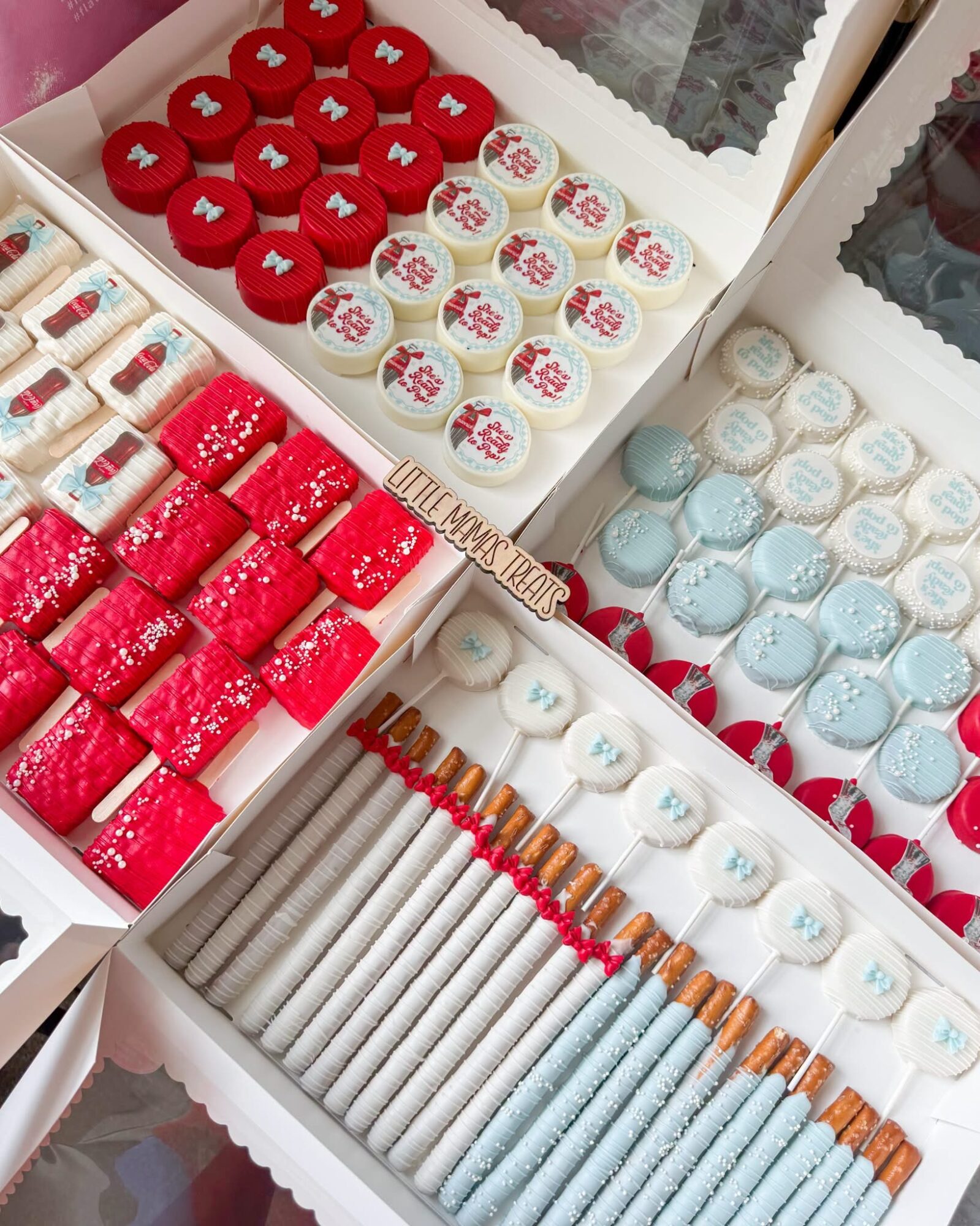 Assorted decorated cookies in boxes, including red, white, and blue themes, with various patterns and designs.