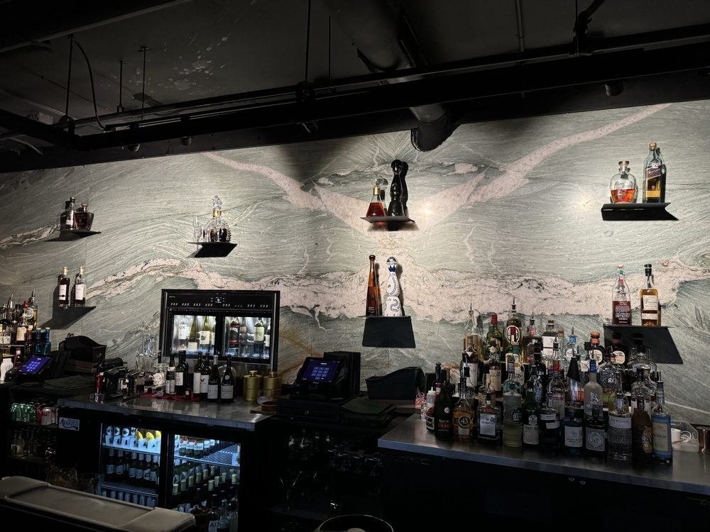Bar with bottles and a large mural of a mountain landscape in the background.