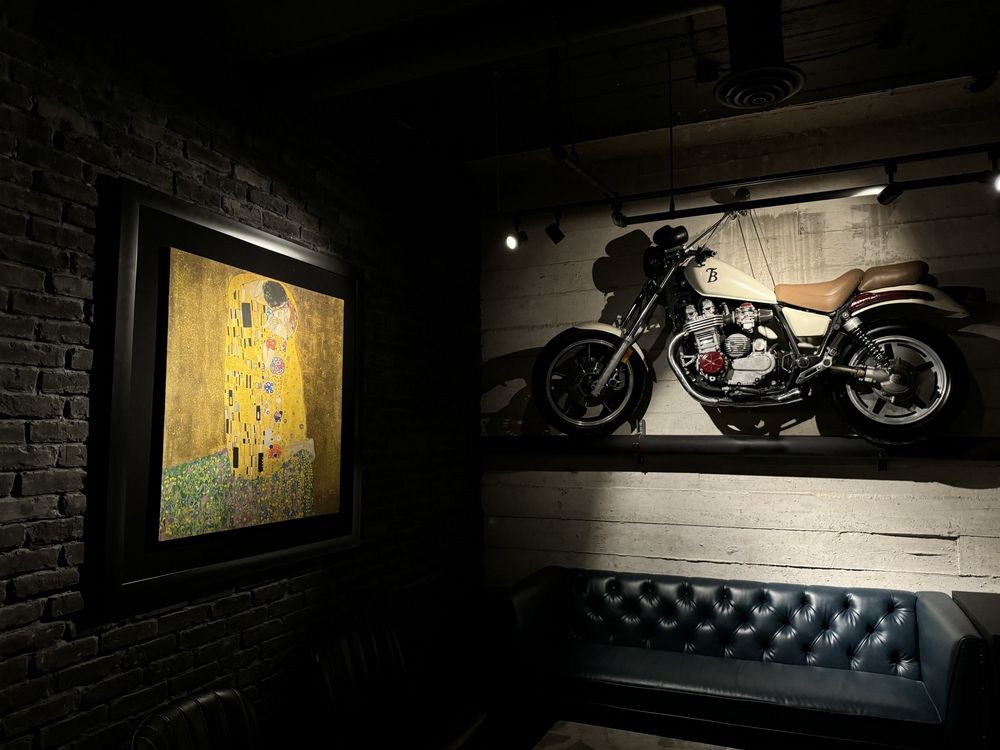 Motorcycle displayed on a wall with a painting on a brick wall in a dimly lit room.