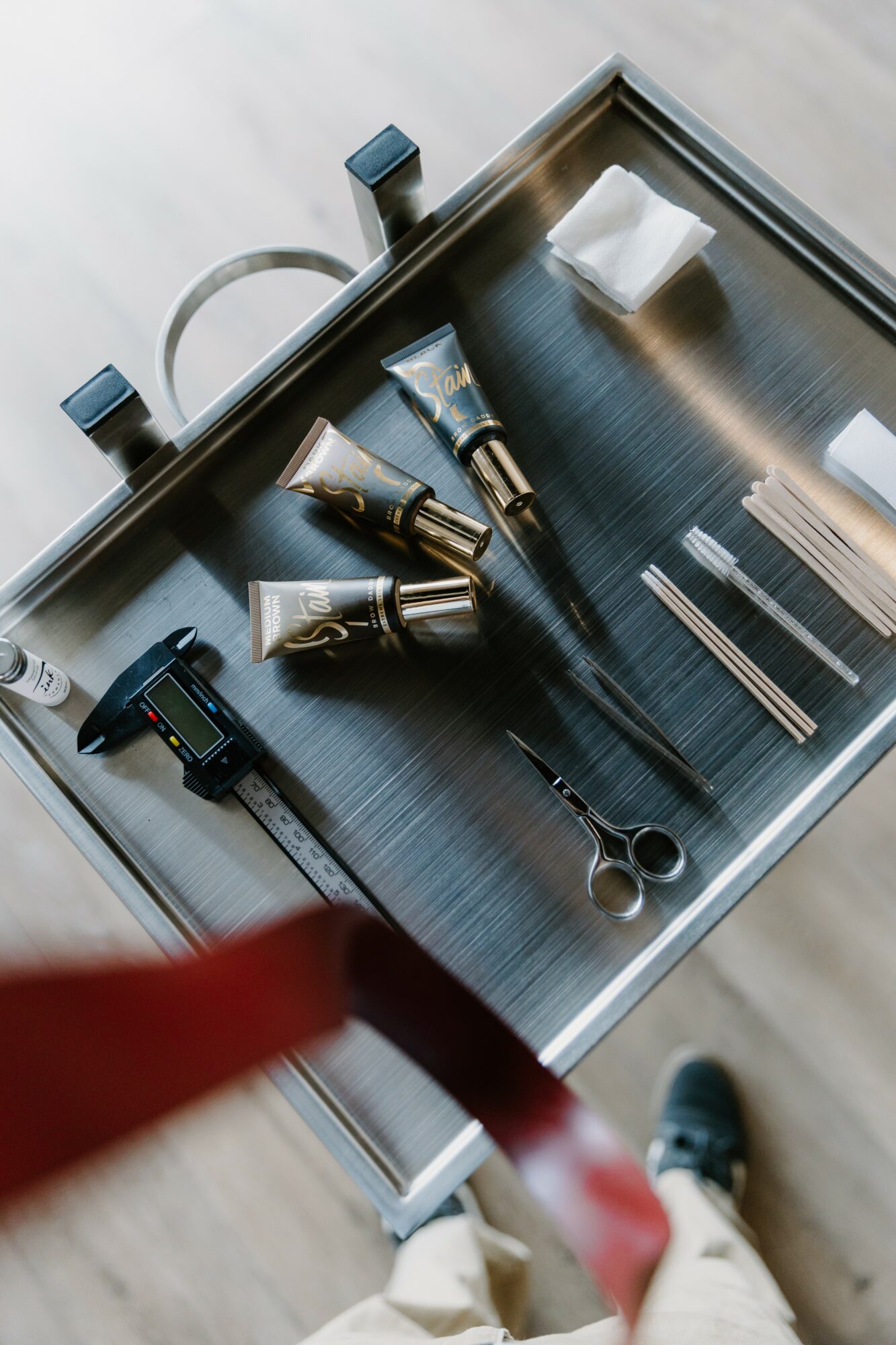 Salon tools including hairbrushes, scissors, and styling products on a black tray, viewed from above.