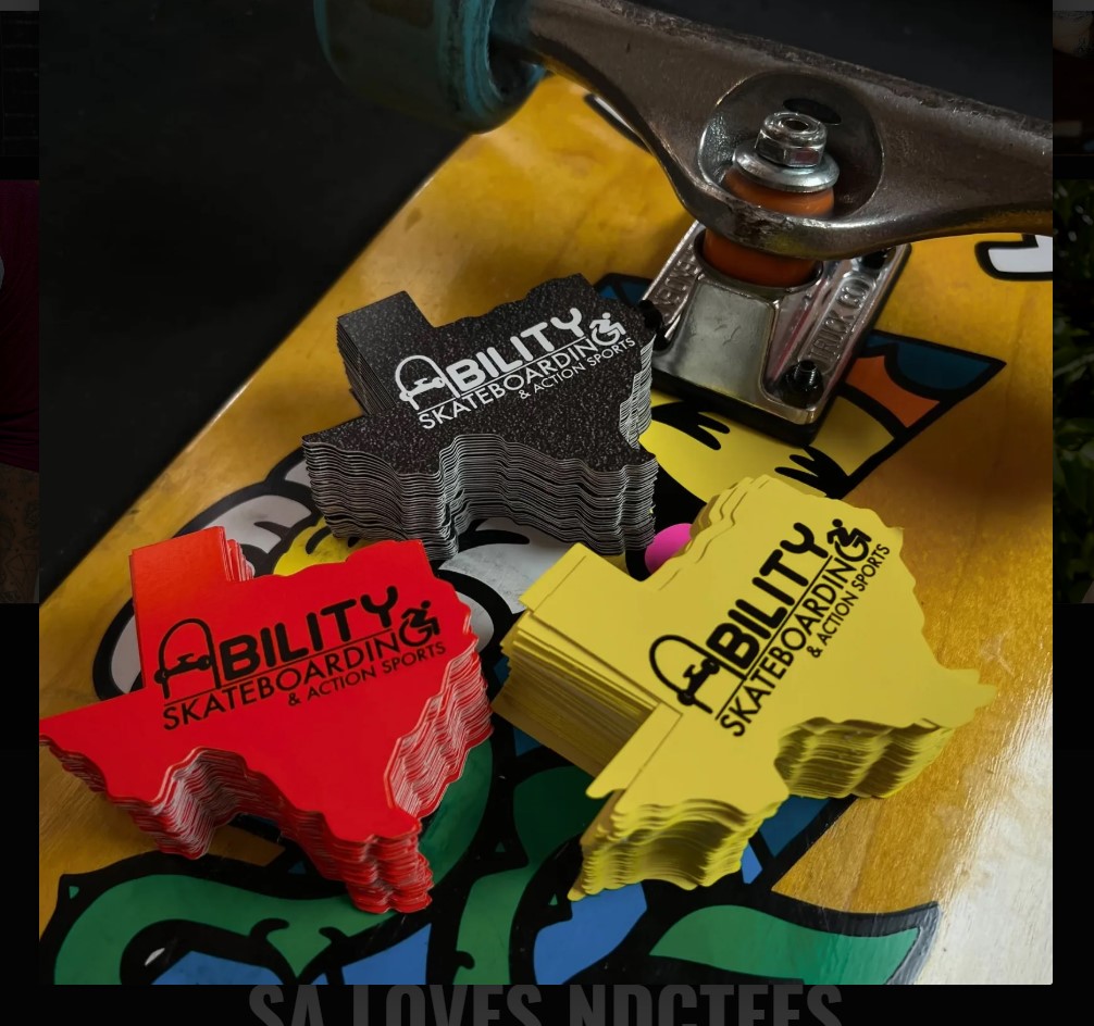 Stacked skateboard grip tapes in black, red, and yellow colors on a skateboard deck with trucks and wheels visible.