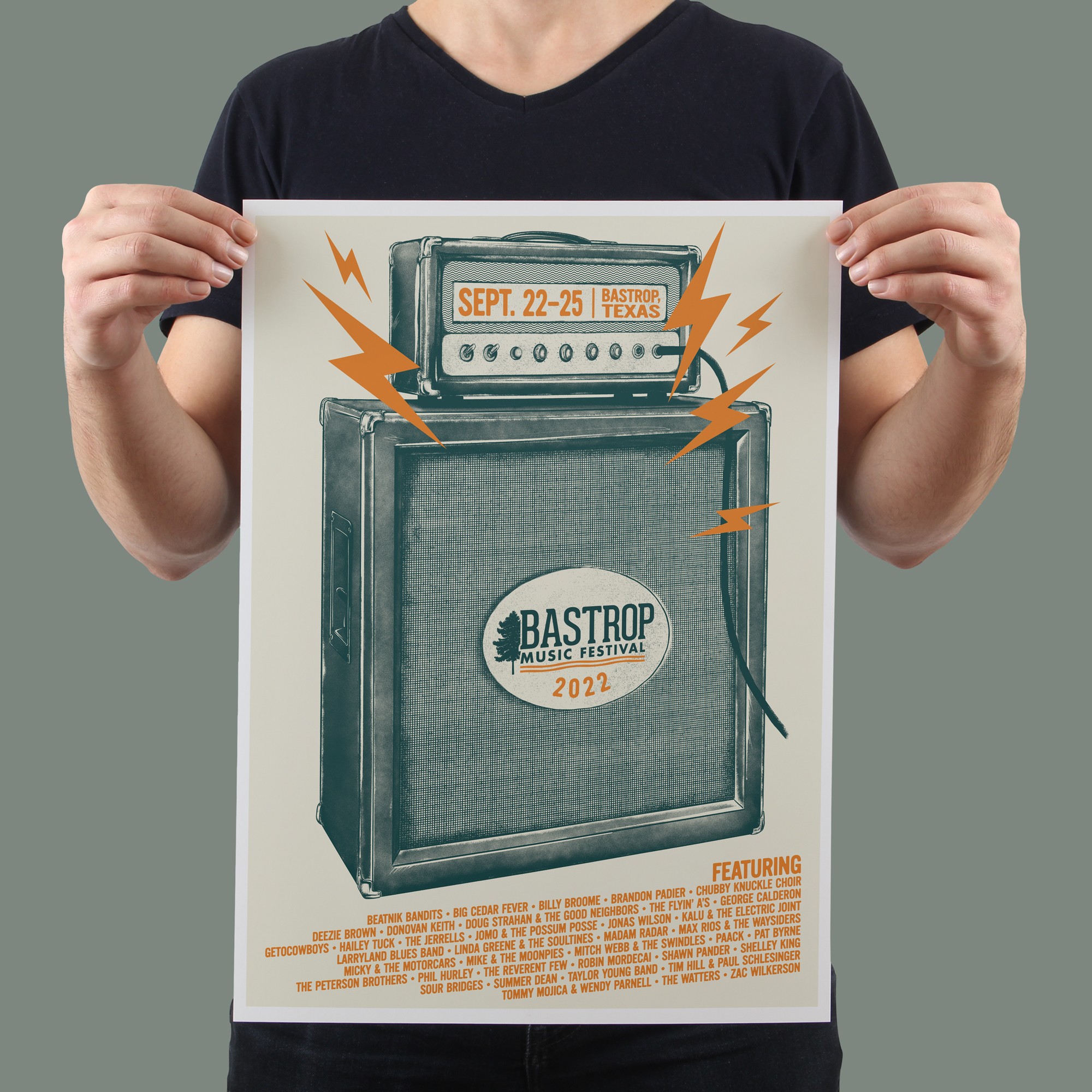 Person holding a poster for Bastrop Music Festival 2022 with guitar amplifier and lightning bolt graphics.