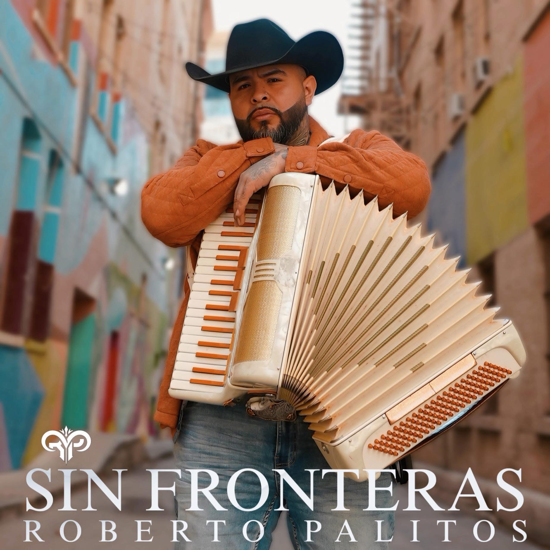 Man wearing cowboy hat holding accordion in colorful urban alleyway, looking at camera, with buildings in background.