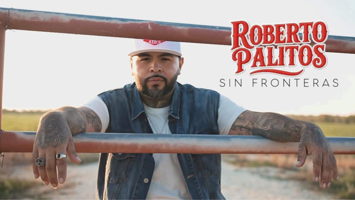 Man with tattoos and a cap leaning on a metal bar outdoors, with text 'Roberto Palitos Sin Fronteras' in the top right.