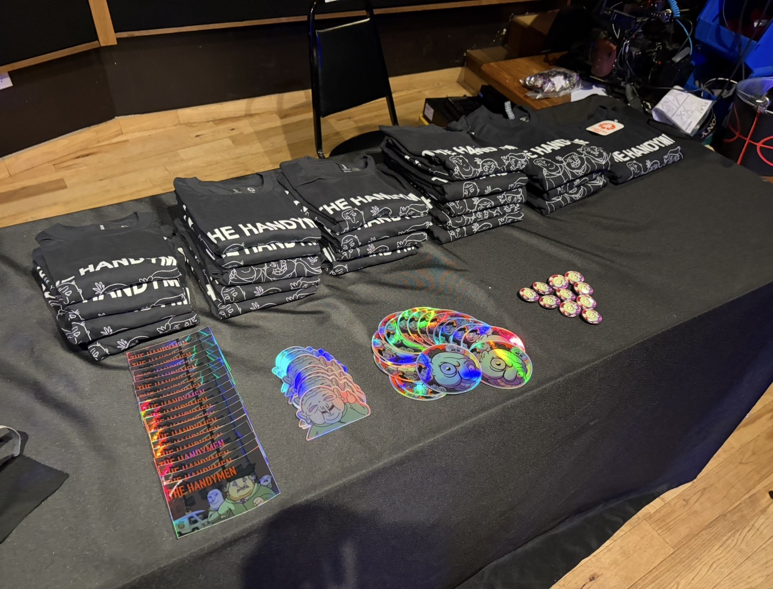Table with black bags, colorful bracelets, and small items, set in a room with wooden flooring and a black tablecloth.