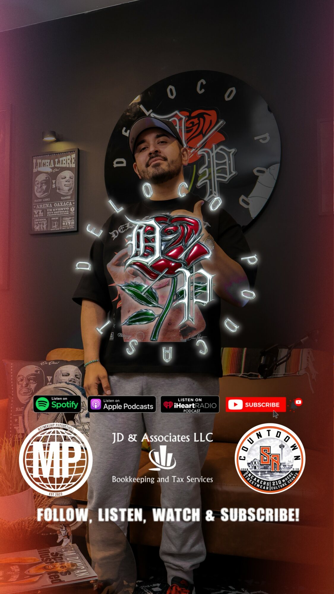 Young man with a beard and cap standing in front of a circular logo, holding a phone, in a room with posters.
