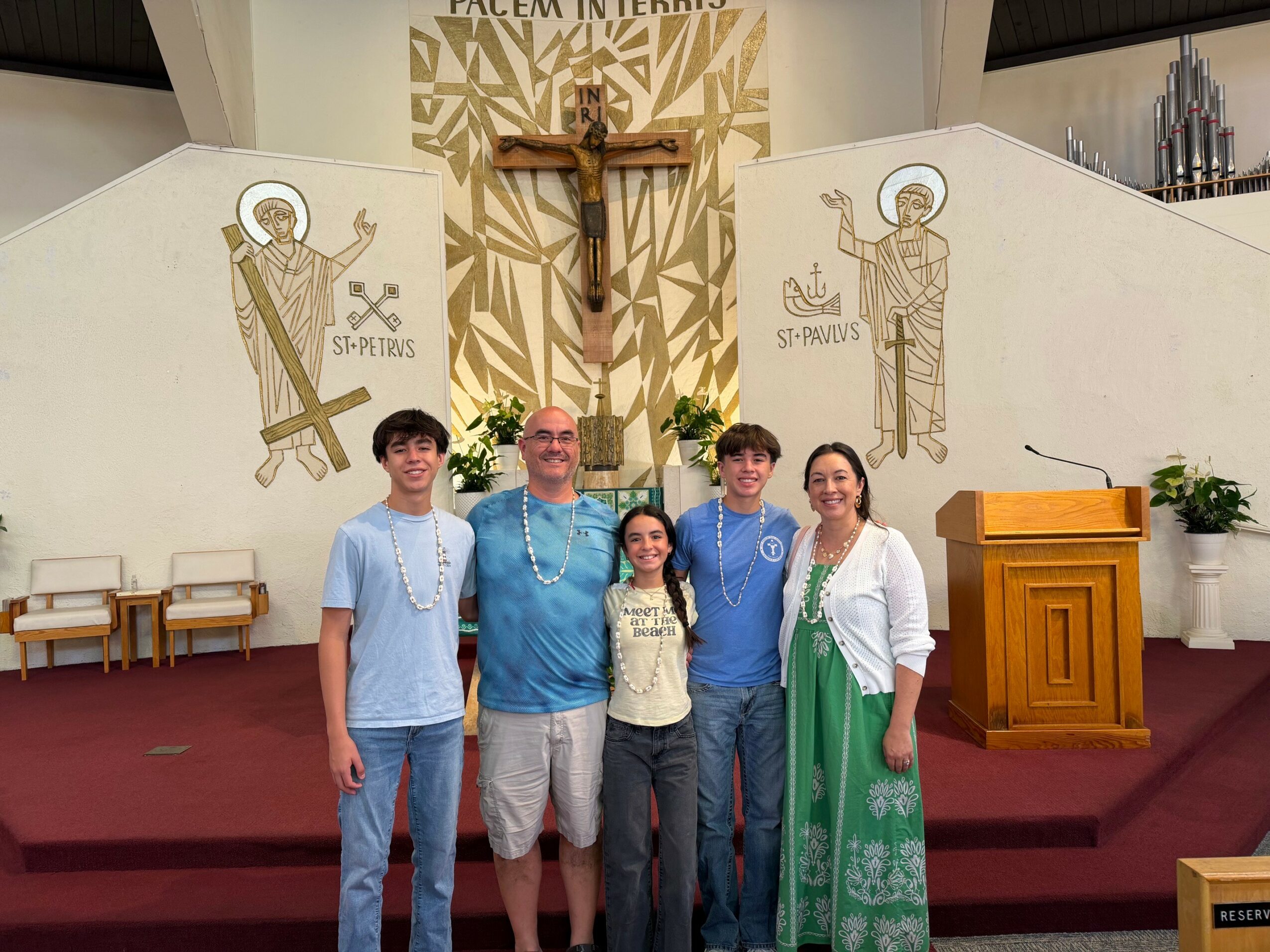 Group of five people standing inside a church near a crucifix and religious artwork, with a wooden pulpit on the right.