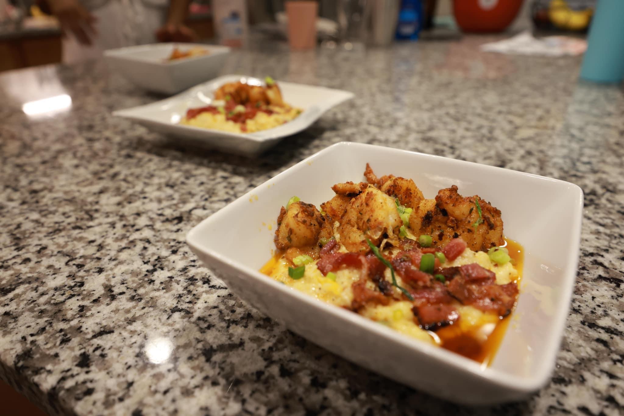 Two white square bowls with food on a speckled gray countertop, one in foreground and one in background, with blurred background.