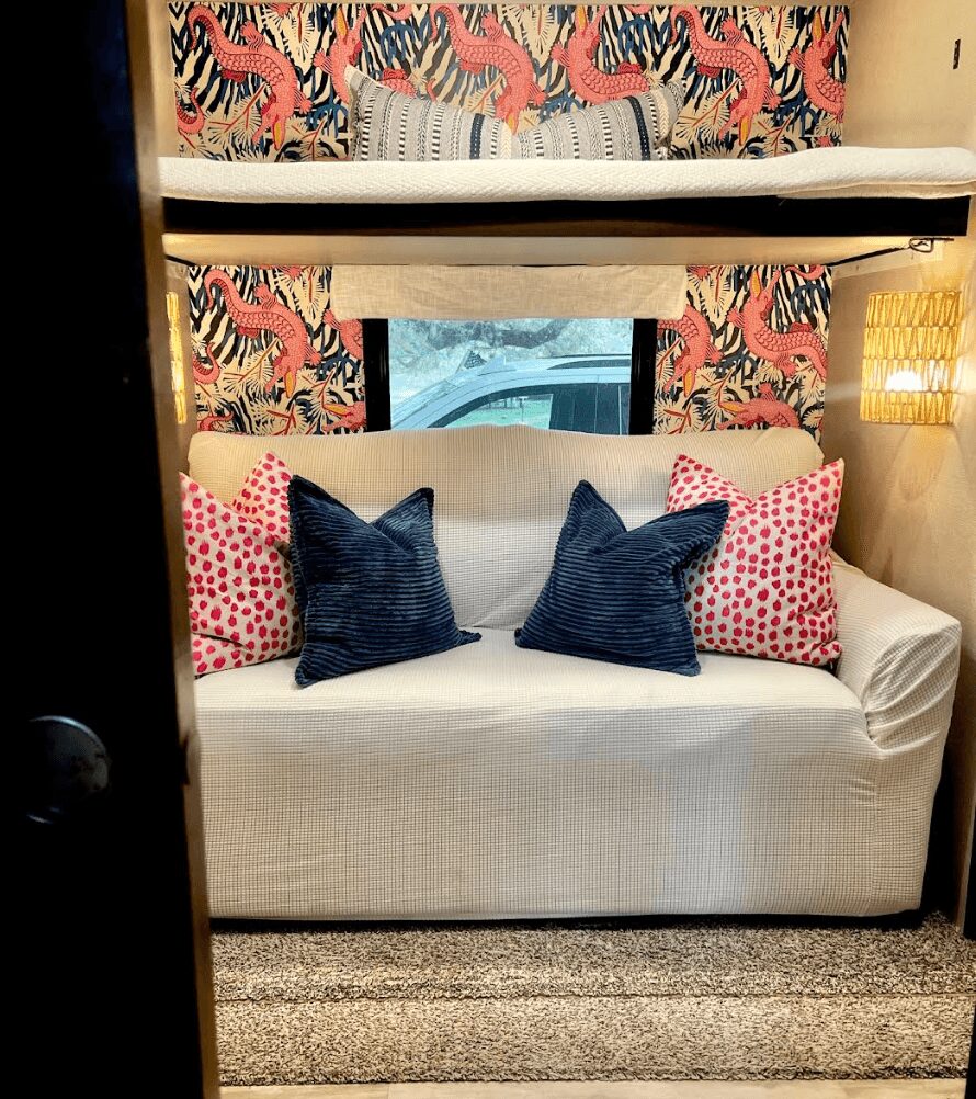 Bunk bed with a window, zebra-patterned wallpaper, and a sofa with pillows in a cozy room.