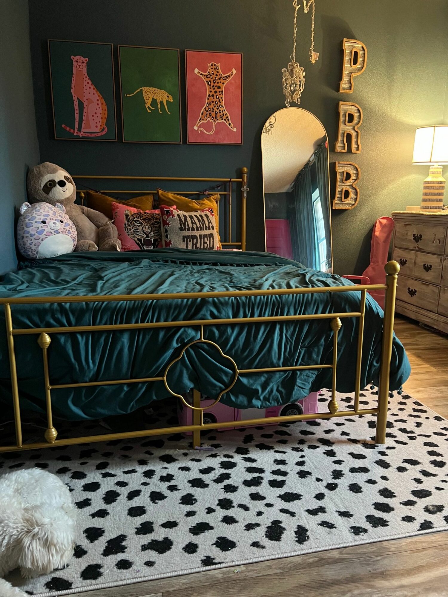 Bedroom with a bed, stuffed animals, and colorful wall art, viewed from the side with a black and white rug.