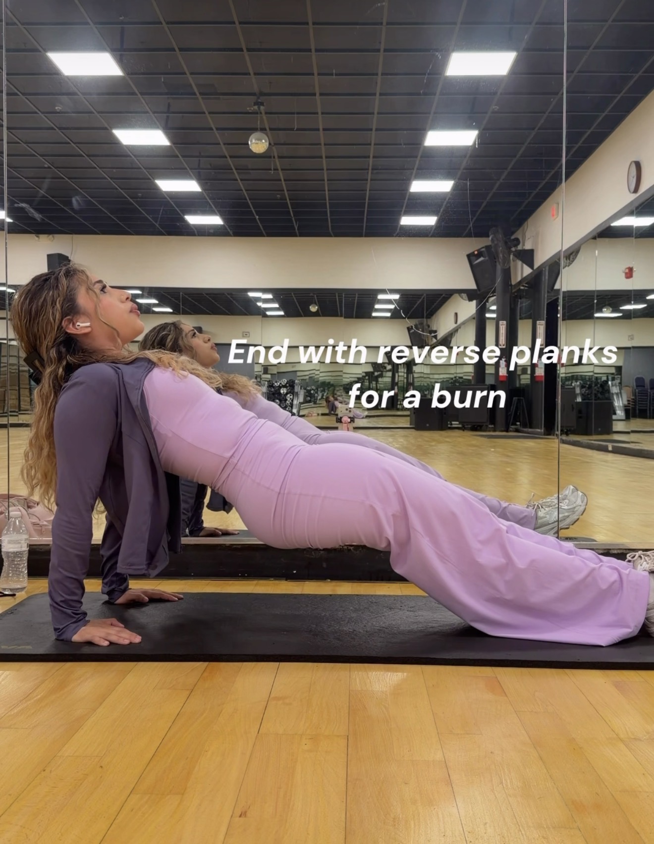 Woman in pink workout clothes performing reverse planks in a gym, with text overlay about exercise for a burn.