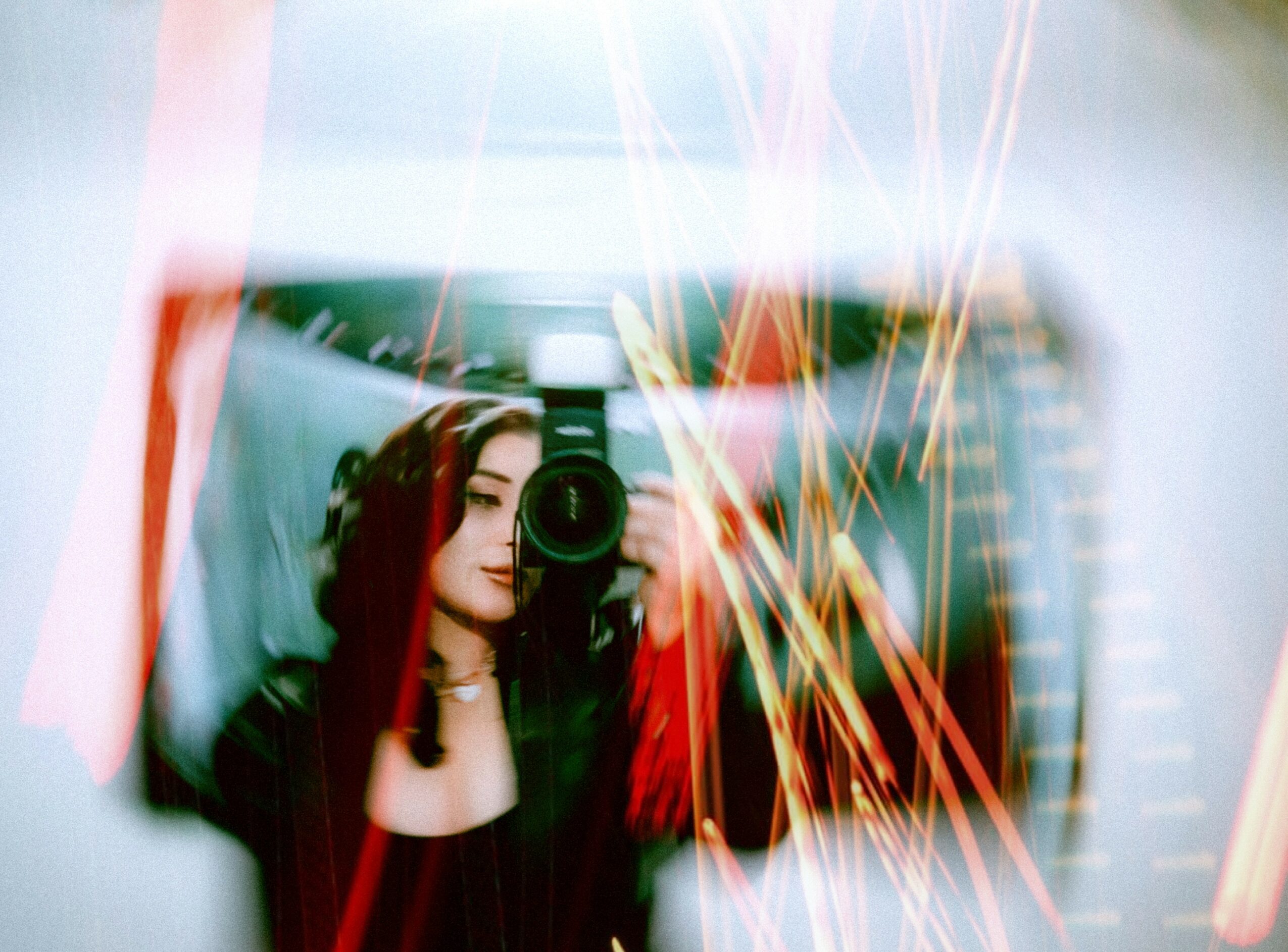 Person taking a mirror selfie with a camera, reflected in a distorted, colorful surface.