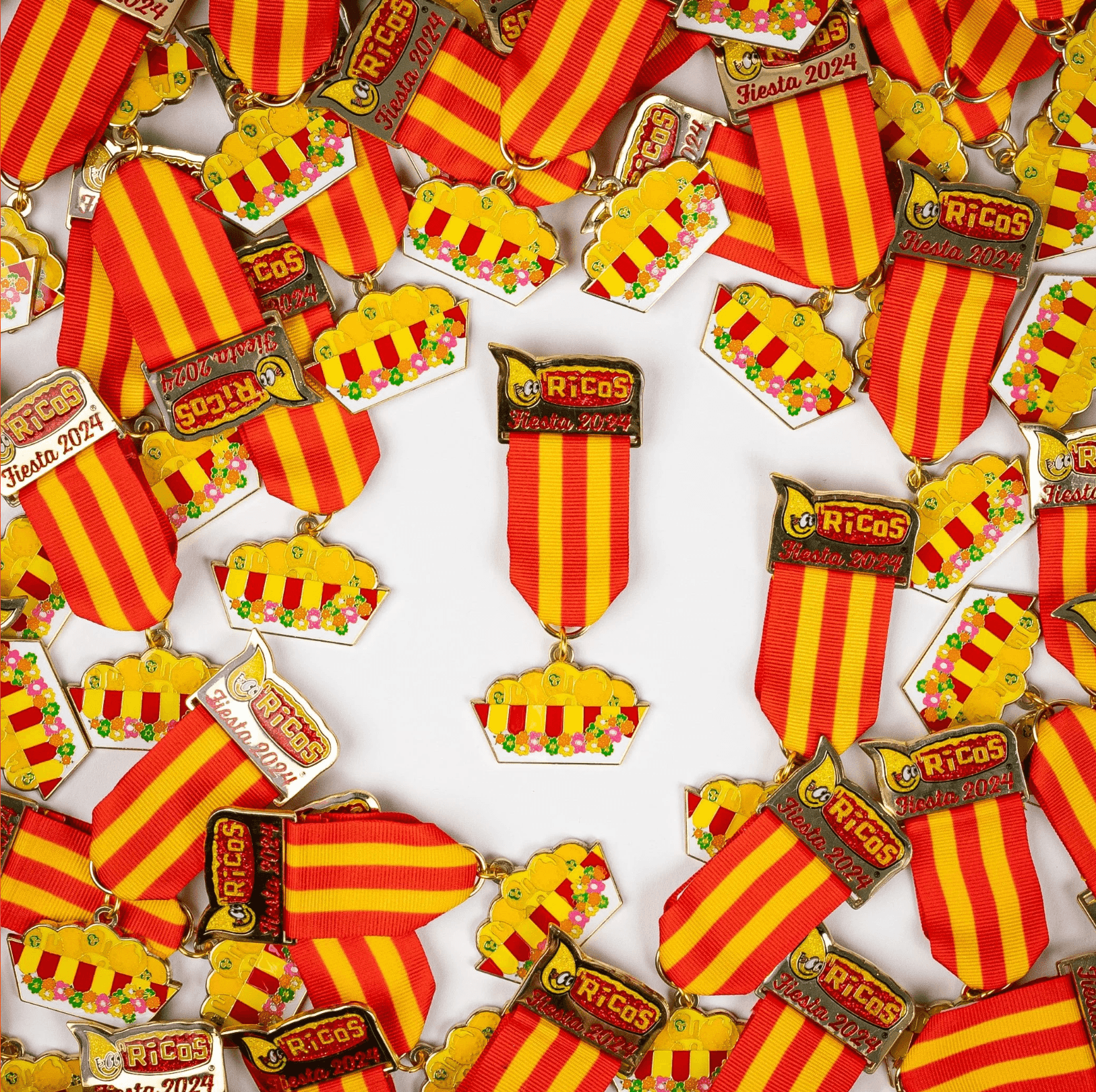 Collection of small toy crowns and striped flags with red and yellow colors, arranged on a white background.