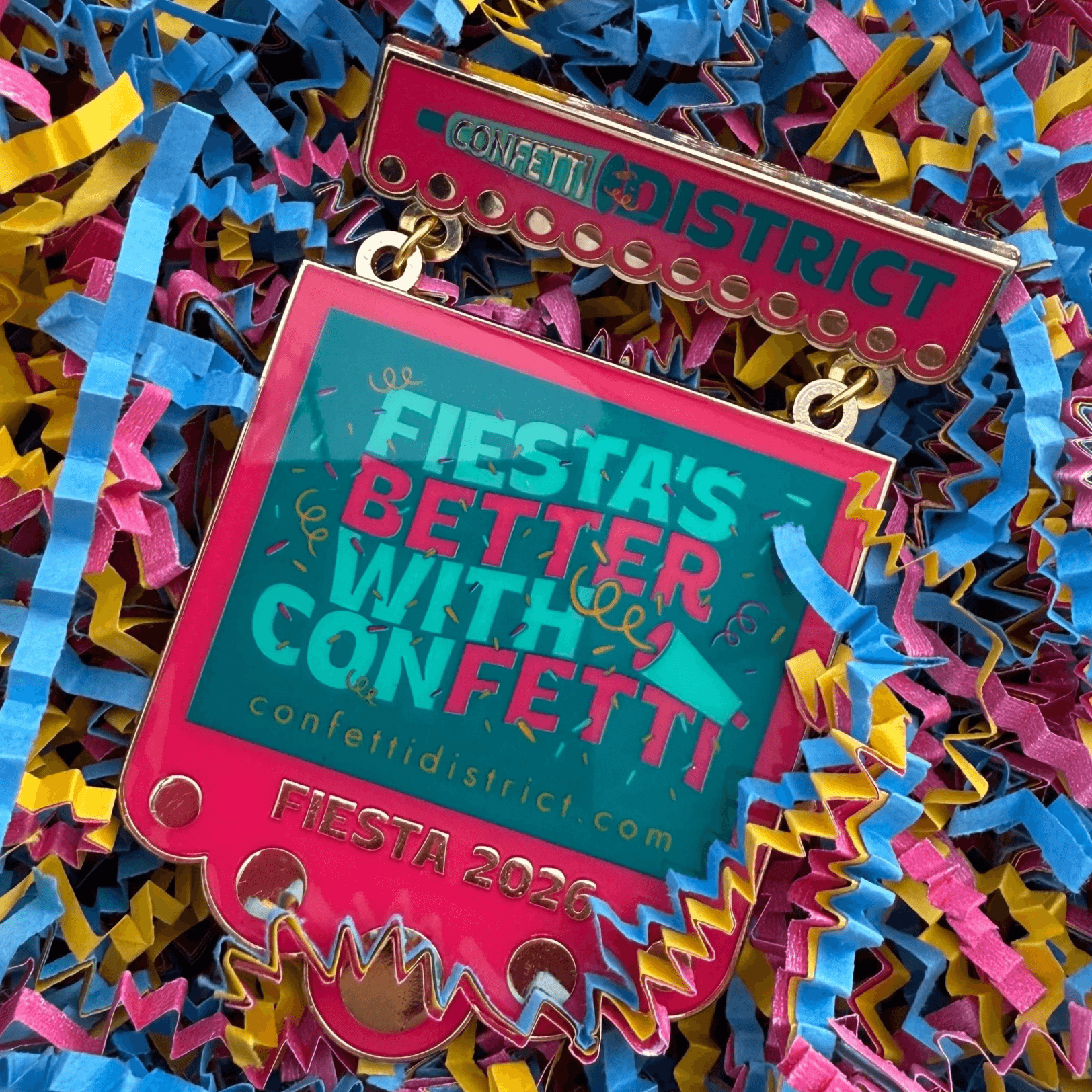 Colorful badge with text about a fiesta, surrounded by multicolored confetti and streamers, celebrating Fiesta 2023.