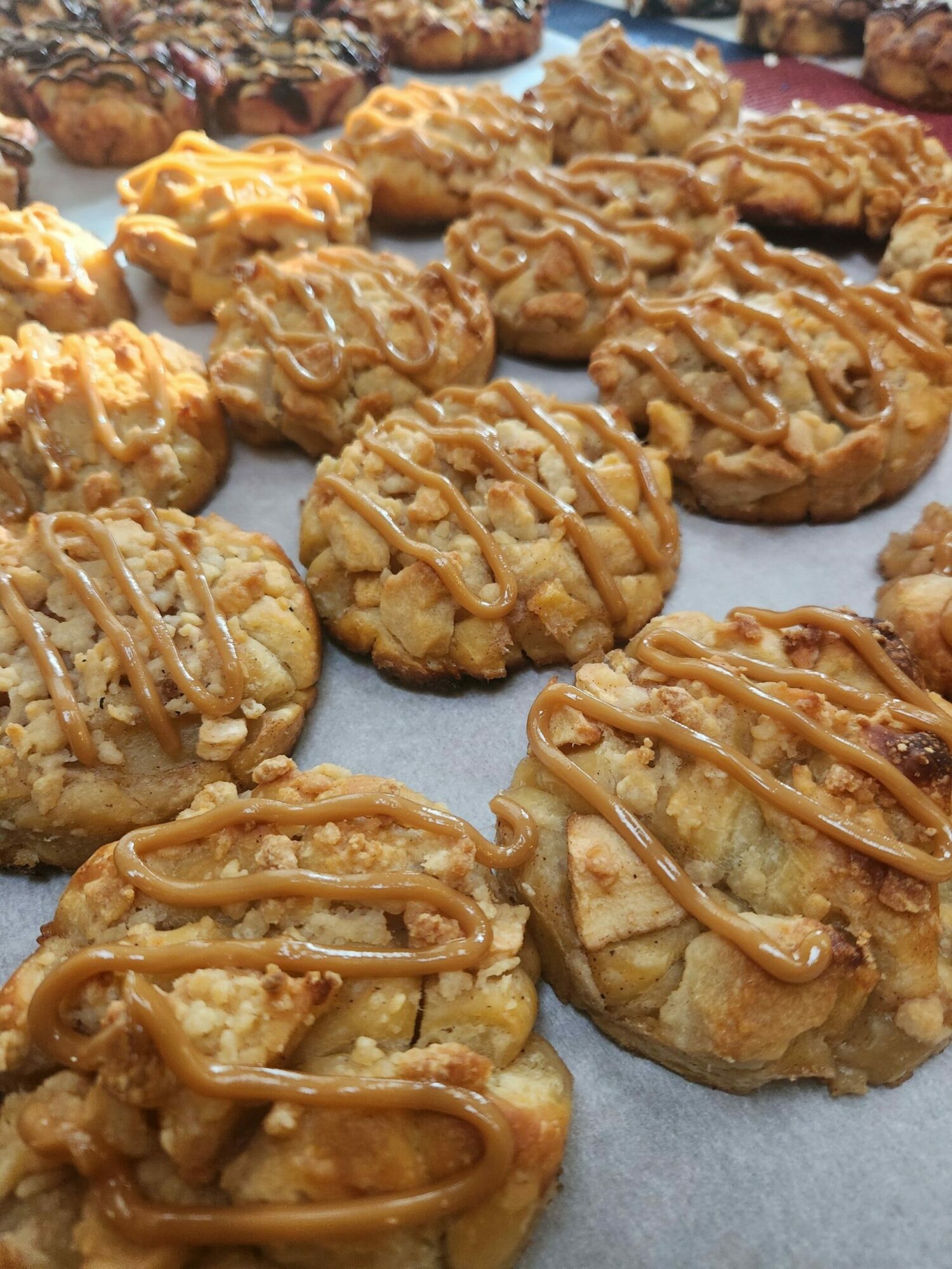 Several cookies with caramel drizzle on top, arranged on a surface, some overlapping each other.