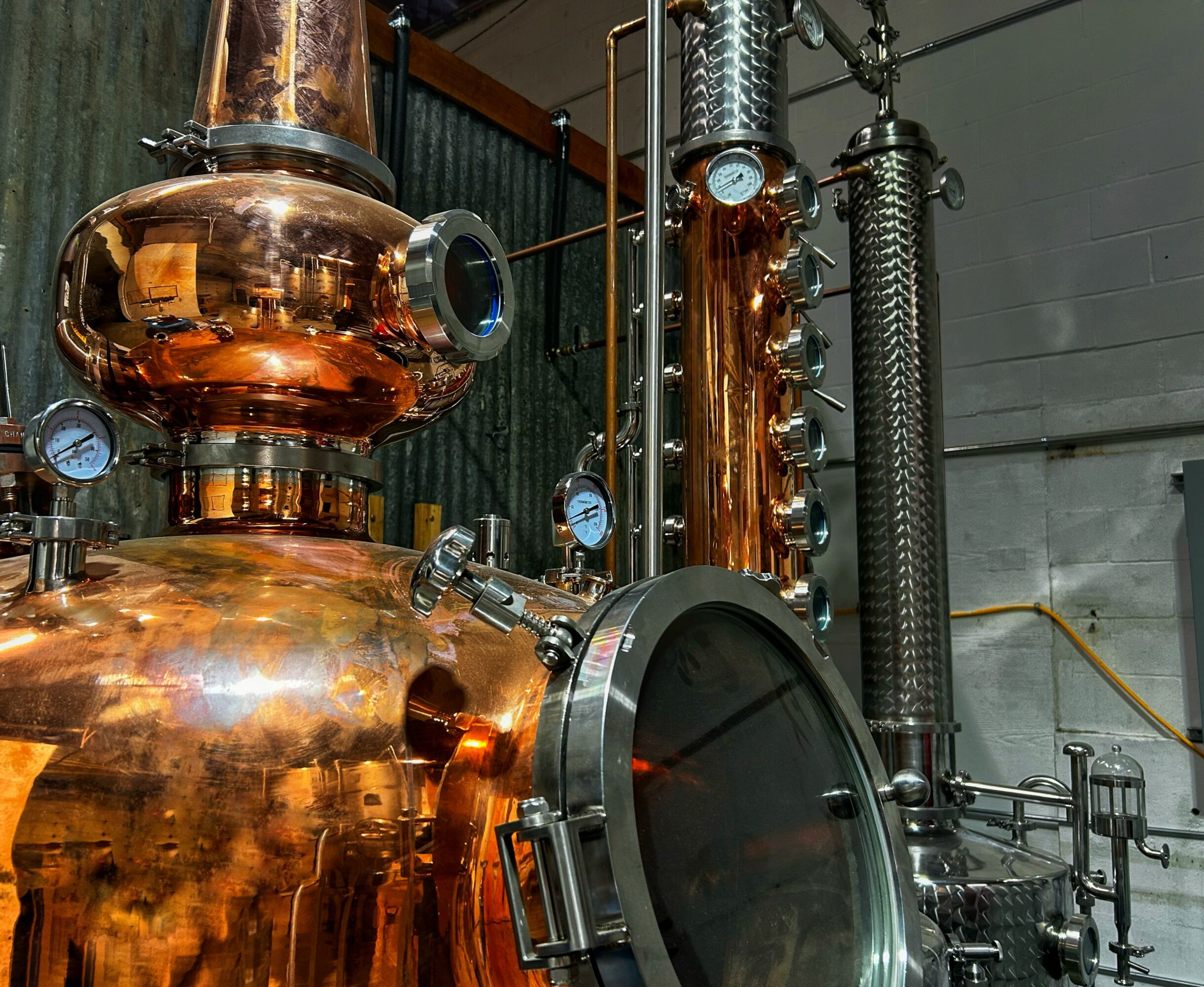 Copper distillation equipment with gauges and pipes in an industrial setting.