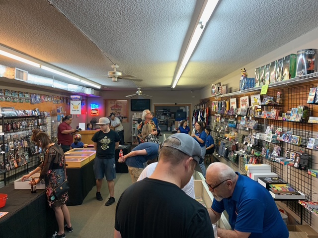 People shopping in a store with shelves filled with various items, some browsing and others working at counters.