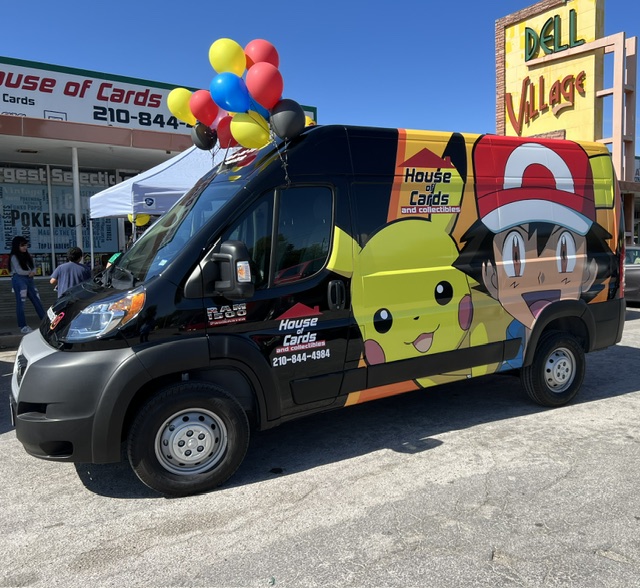 Black van decorated with Pikachu and Ash Ketchum from Pokémon, balloons on top, parked outside a store with a sign reading 'House of Cards'.