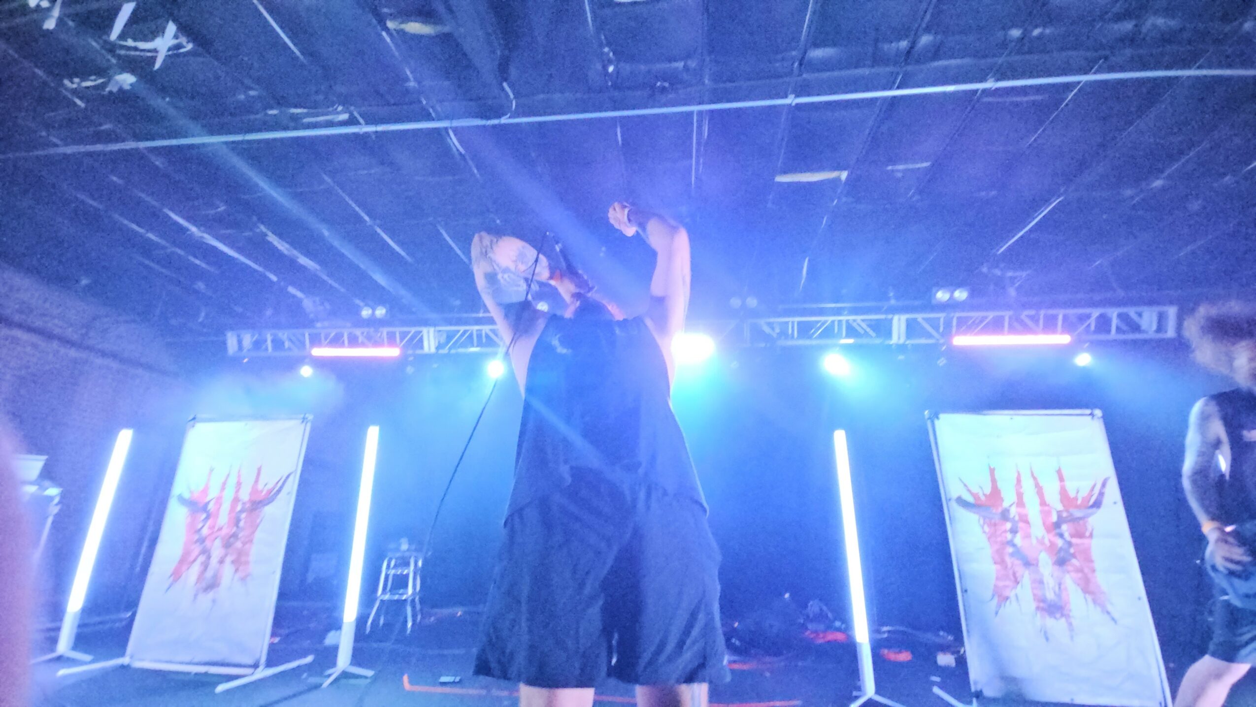 Two people on stage with bright lights and screens displaying abstract designs behind them.
