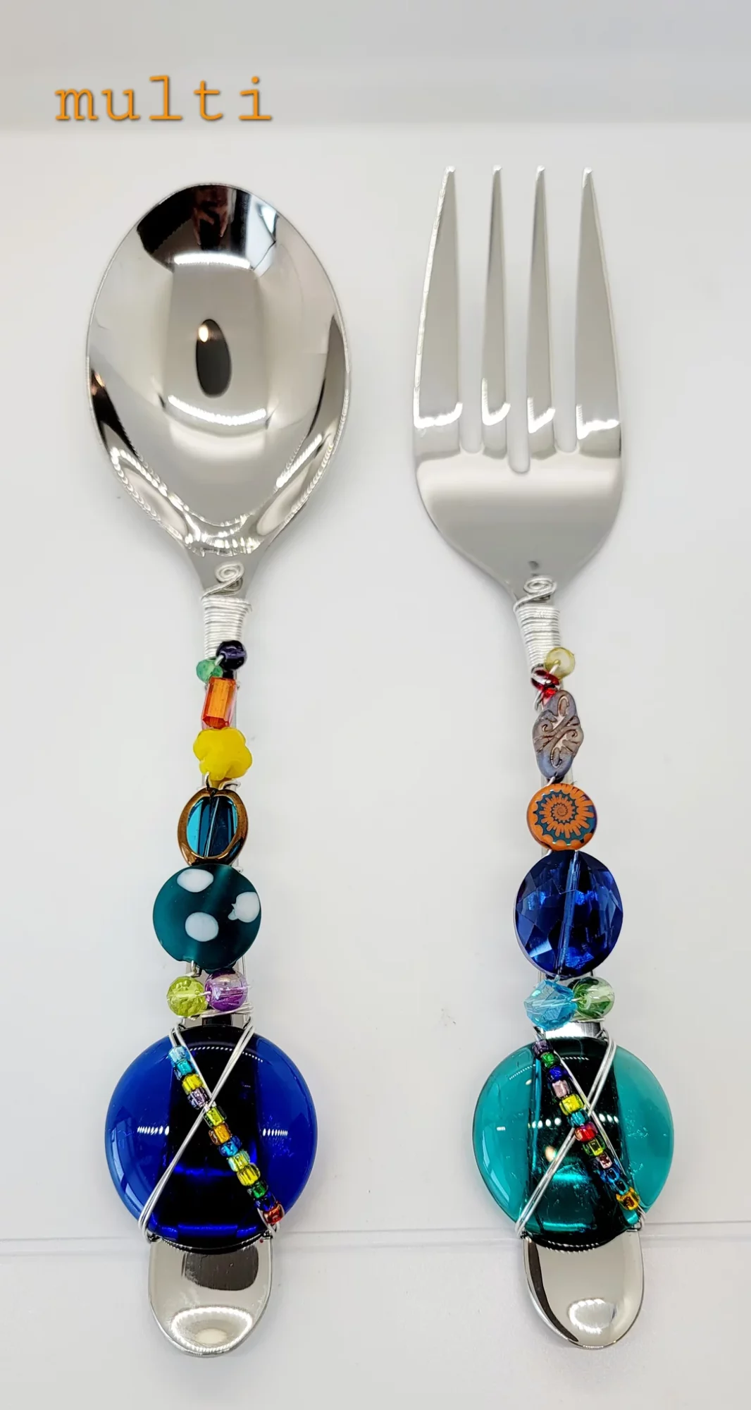 Two decorated utensils, a spoon and a fork, with colorful beaded handles, displayed vertically against a white background.