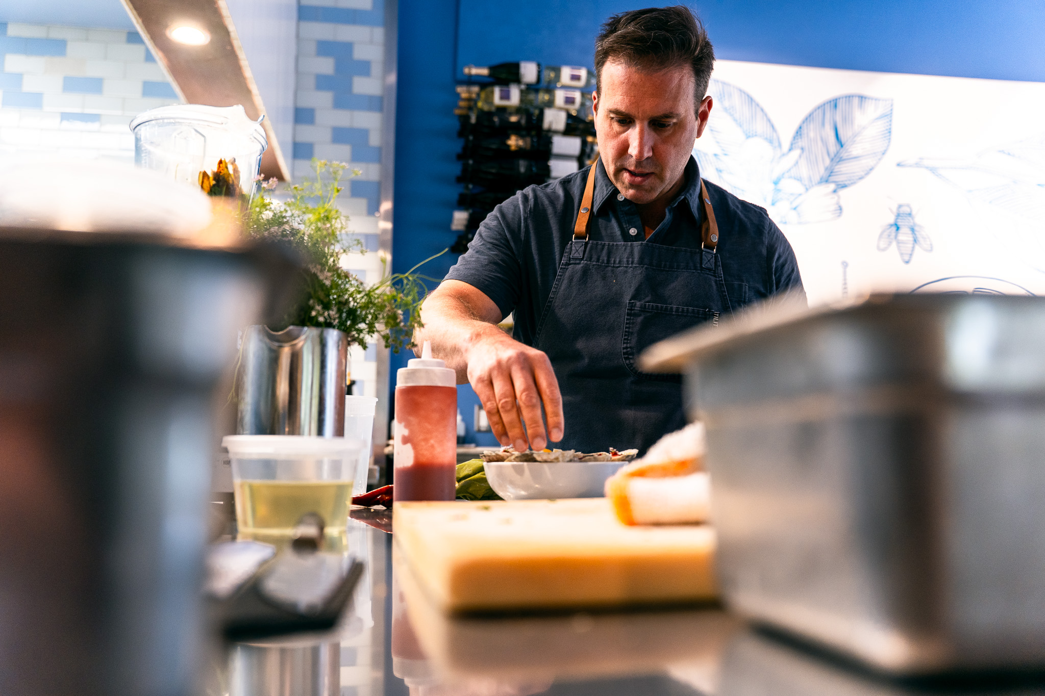 Man preparing food in a kitchen with various utensils and ingredients on the counter.