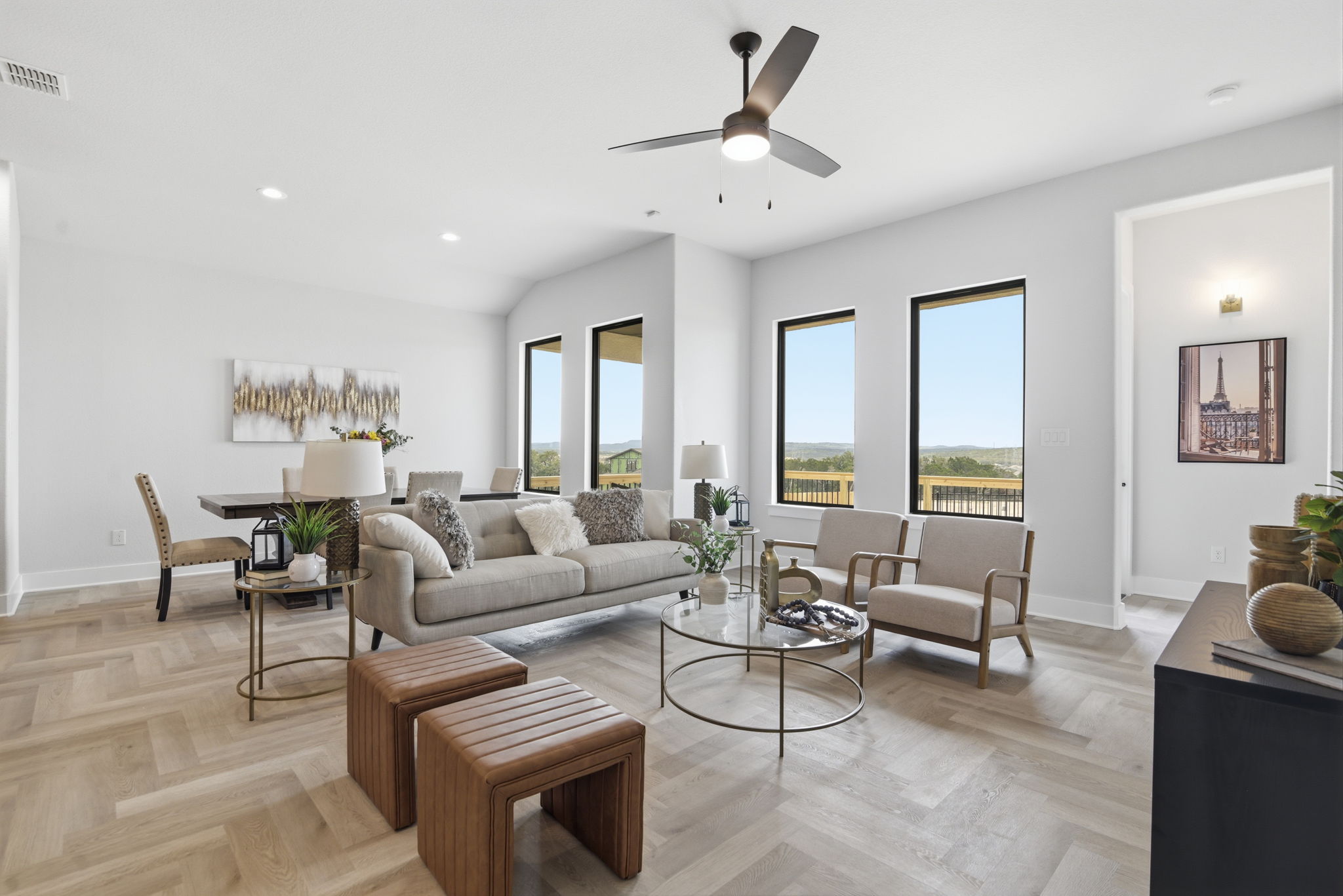 Bright living room with large windows, sofa, armchairs, coffee table, and wooden flooring.