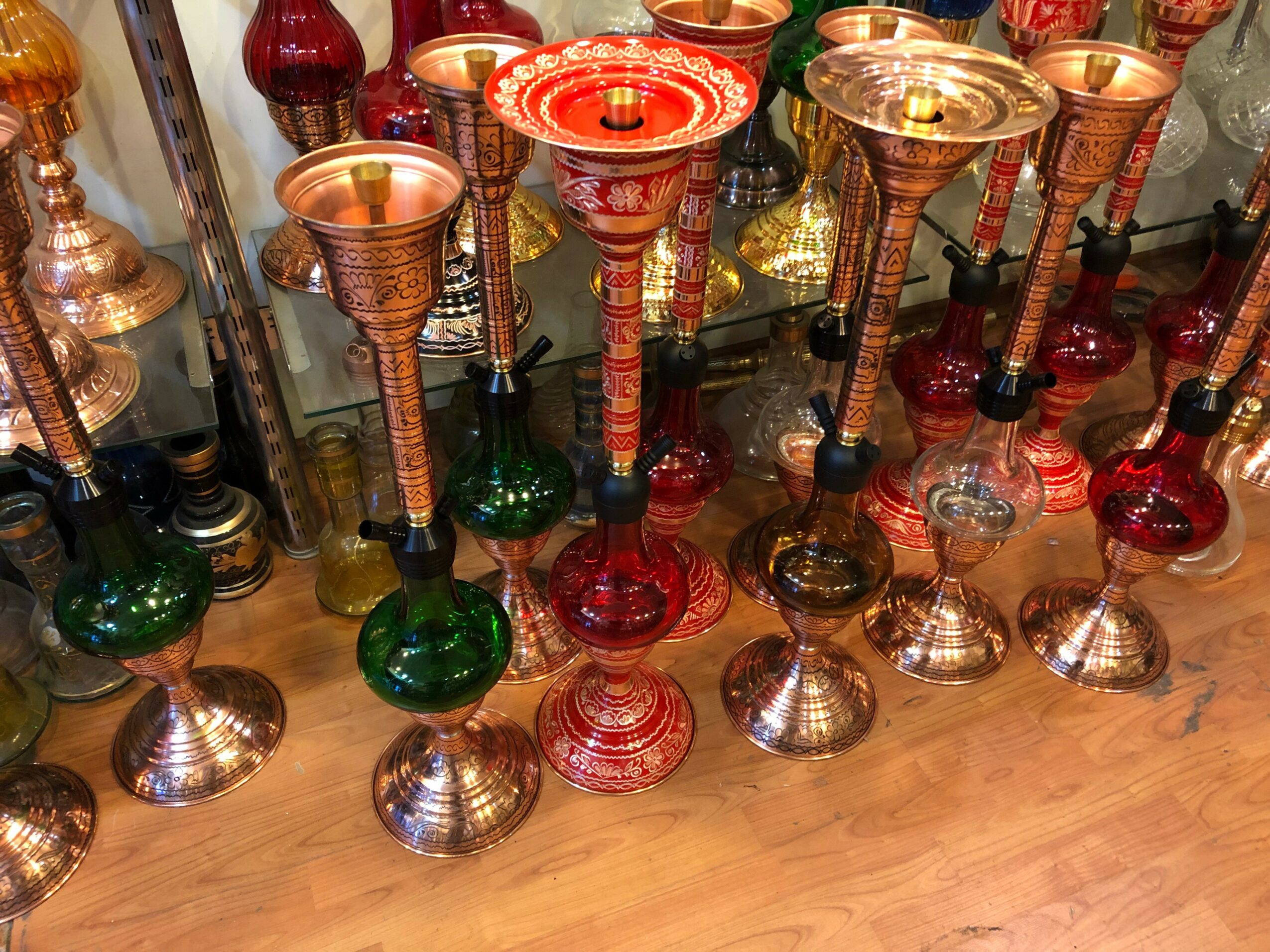 Collection of colorful glass and metal candlesticks arranged on a wooden surface, with various shapes and sizes.