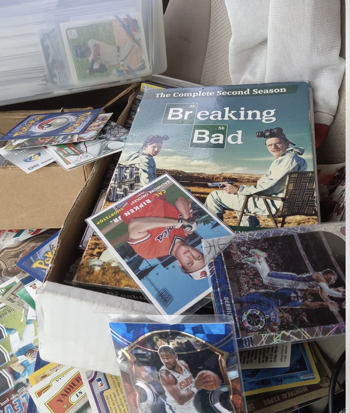 A collection of DVDs and magazines, including 'Breaking Bad' season two, scattered on a surface with some stacked and overlapping.