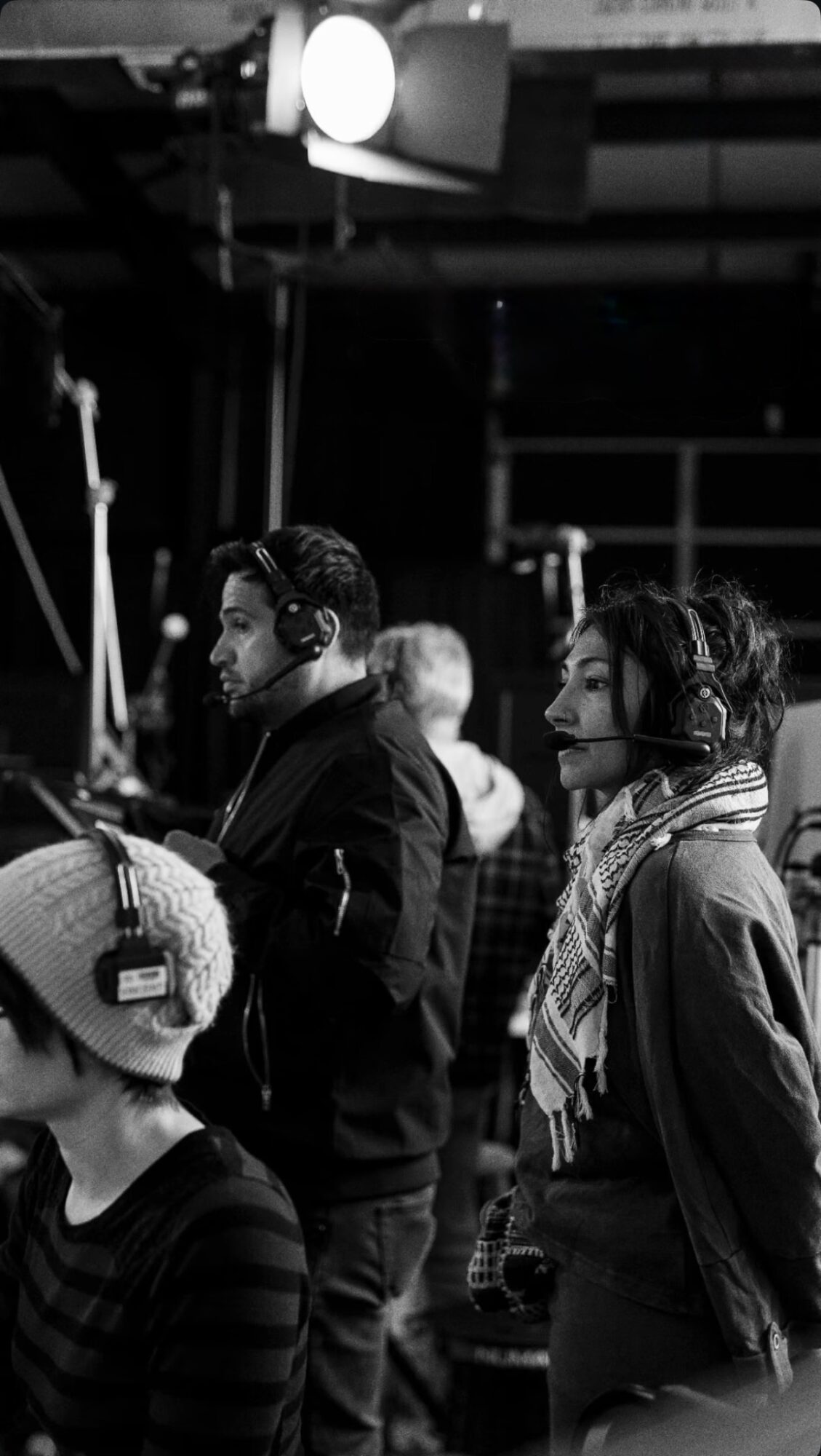 Group of people in a studio or control room, some wearing headsets, with equipment and lighting visible.