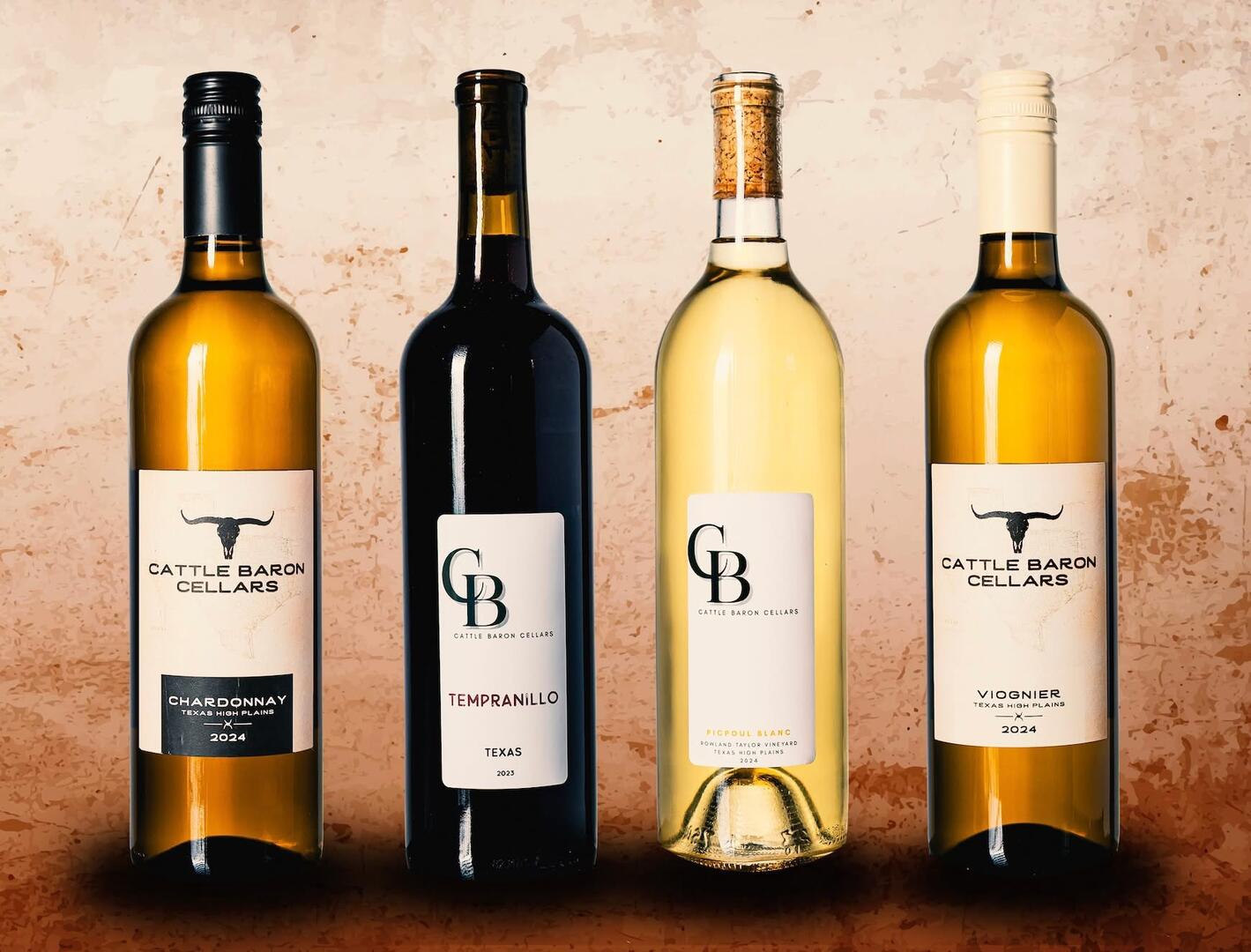 Four wine bottles lined up on a surface against a textured background, with labels visible. Word count: 20.