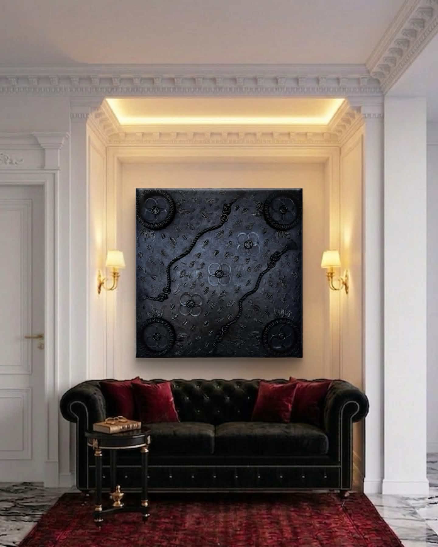 Living room corner with a black sofa, red pillows, wall art, and wall sconces, with white walls and ceiling molding.