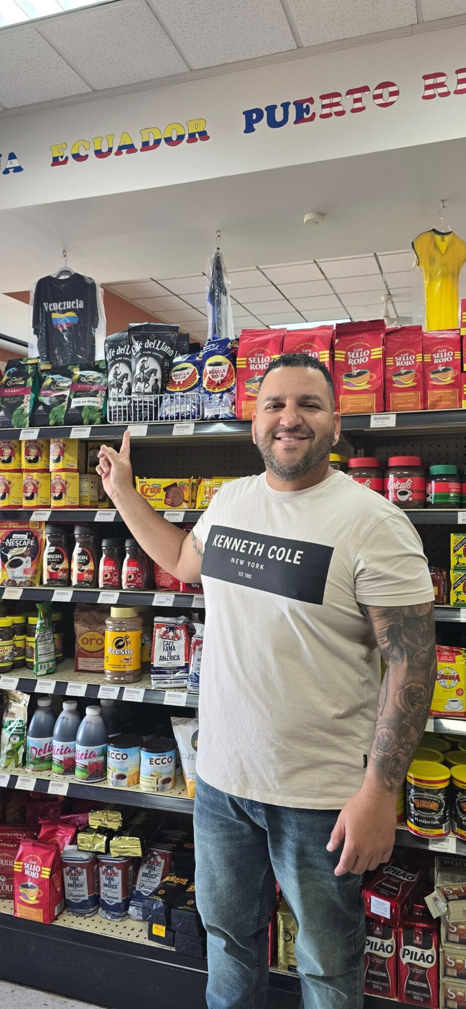 Person standing in a store aisle holding a sign, surrounded by shelves of products, with a yellow object above.