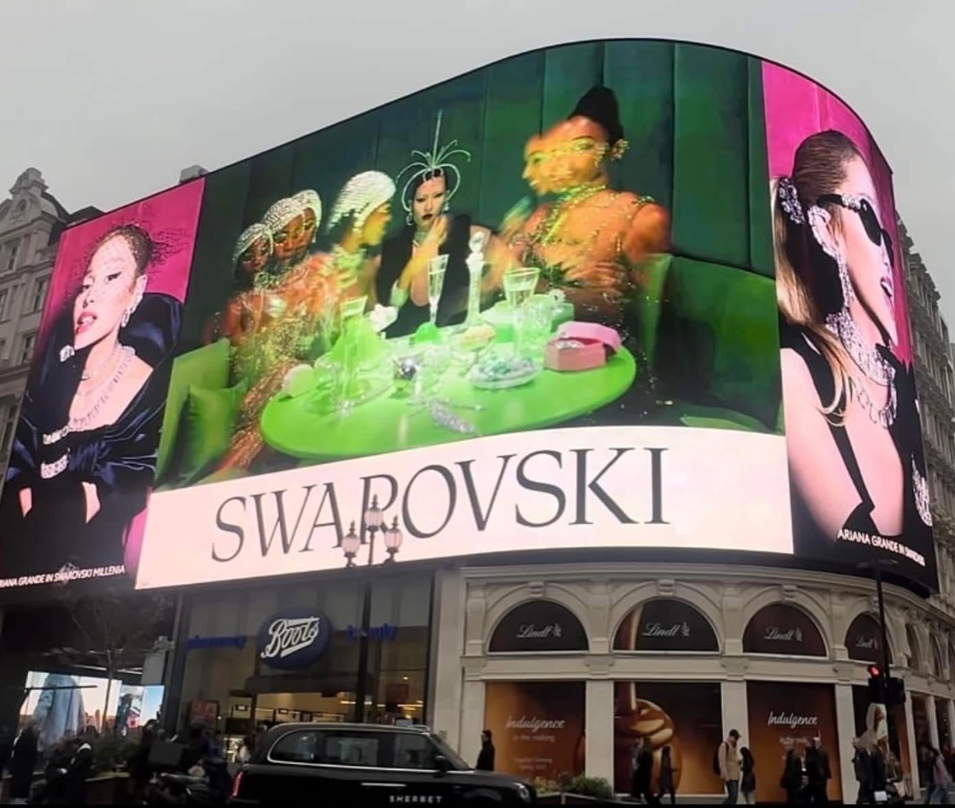 Large curved billboard with fashion images and a central display, featuring the text 'SWAROVSKI'.